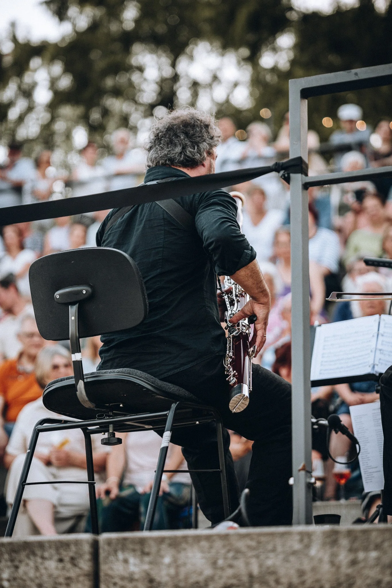 Ein Mann sitzt auf einem Rollstuhl, spielt Klarinette bei einem Konzert im Freien, im Hintergrund eine Menschenmenge. Marvin Lahrs Musikevent Fotograf Koblenz