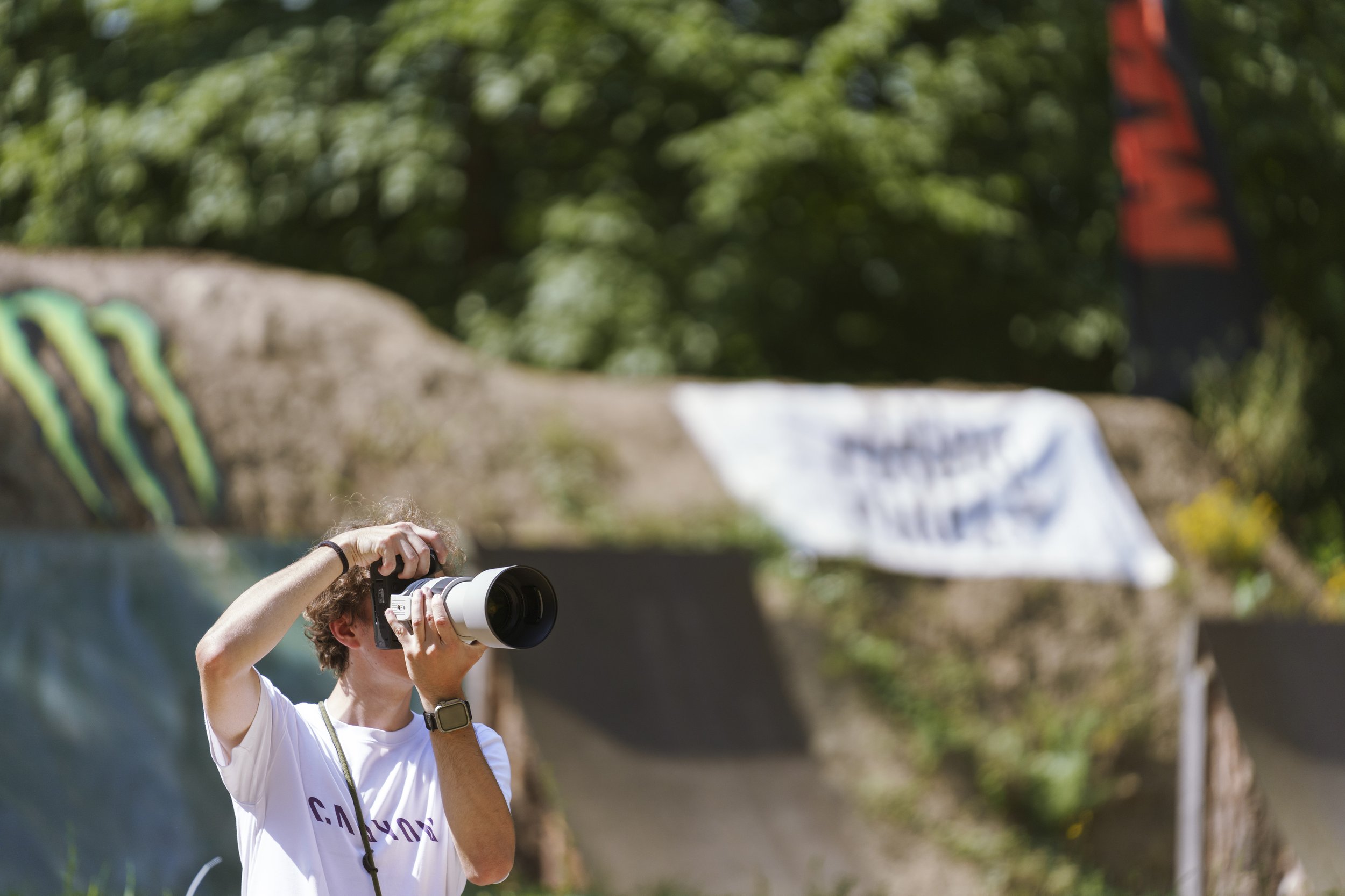 Person mit Kamera beim Fotografieren im Freien, grüne Bäume im Hintergrund. Marvin Lahrs aus Koblenz Fotografiert