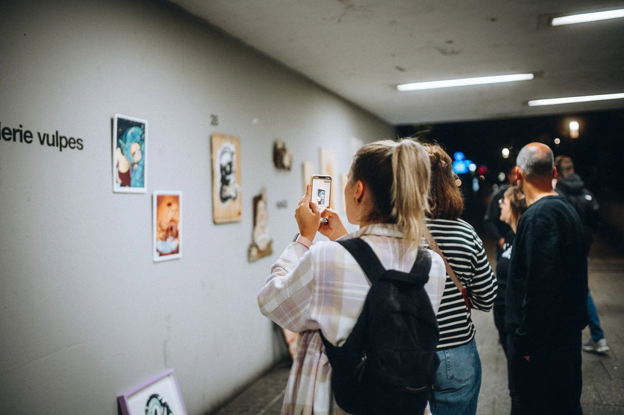Gäste schlendern durch einen Ausstellungsflur mit Bildern – Kultur- und Eventfotografie