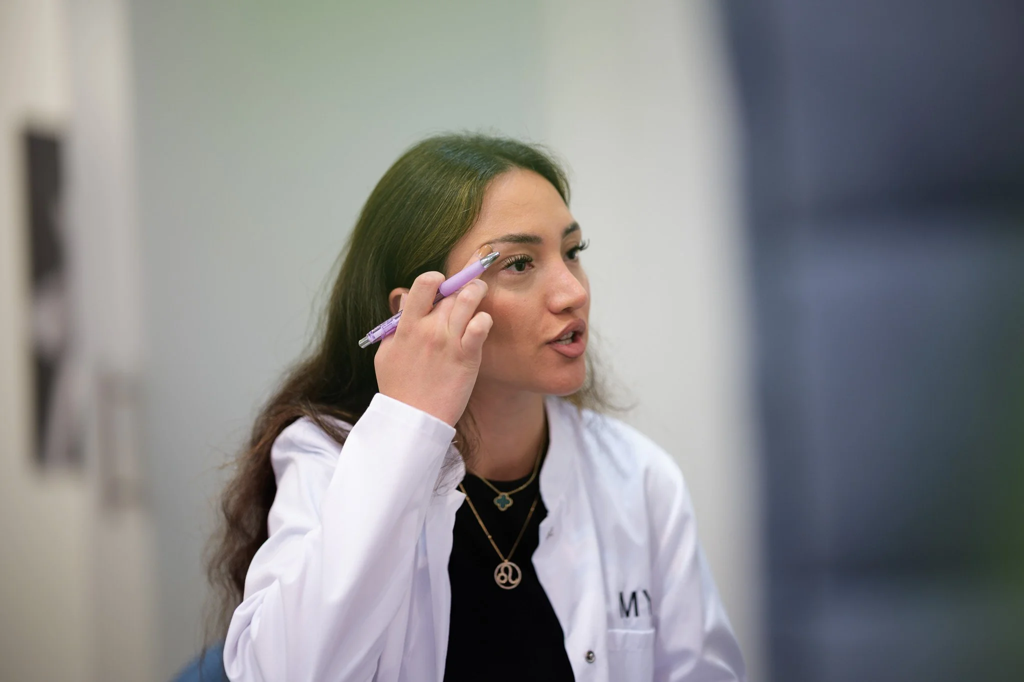 Ärztin mit dunklen Haaren trägt weißen Kittel und hält einen Stift, während sie in einer Klinik oder Praxis arbeitet. Marvin Lahrs Businessfotograf aus Koblenz