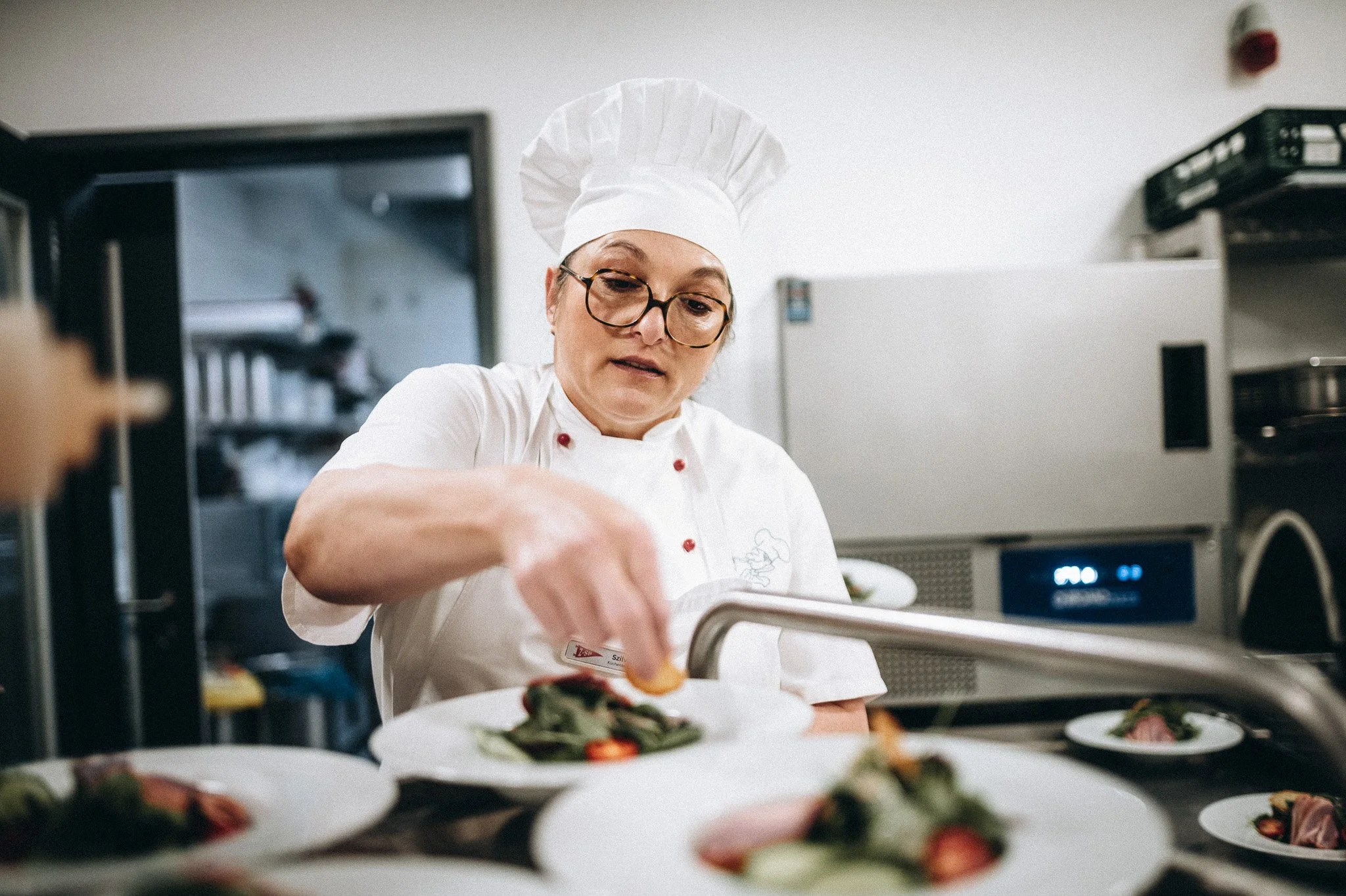 Köchin richtet Teller in der Küche an – Gastronomie- und Hotelfotografie Koblenz