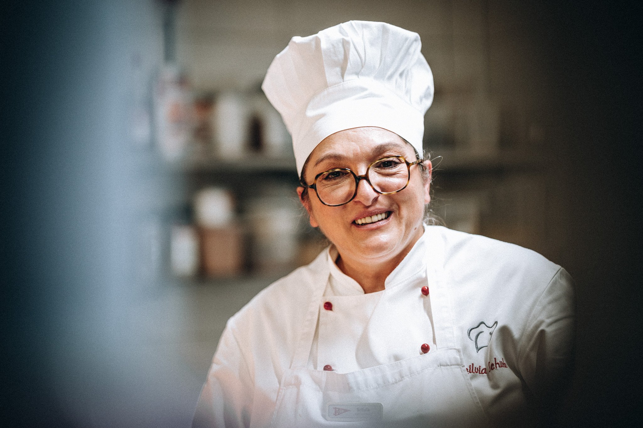 Lachende Köchin mit Kochmütze in der Hotelküche – Mitarbeiterportrait Gastronomie