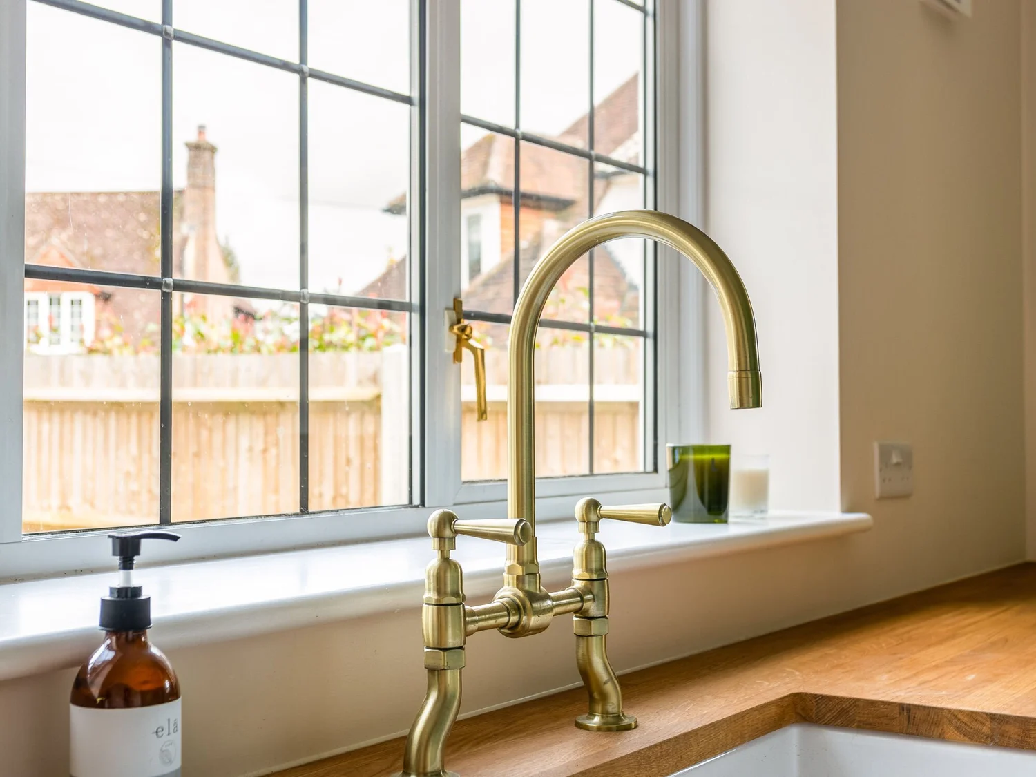 Brass utility-room tap and sink set beneath a window
