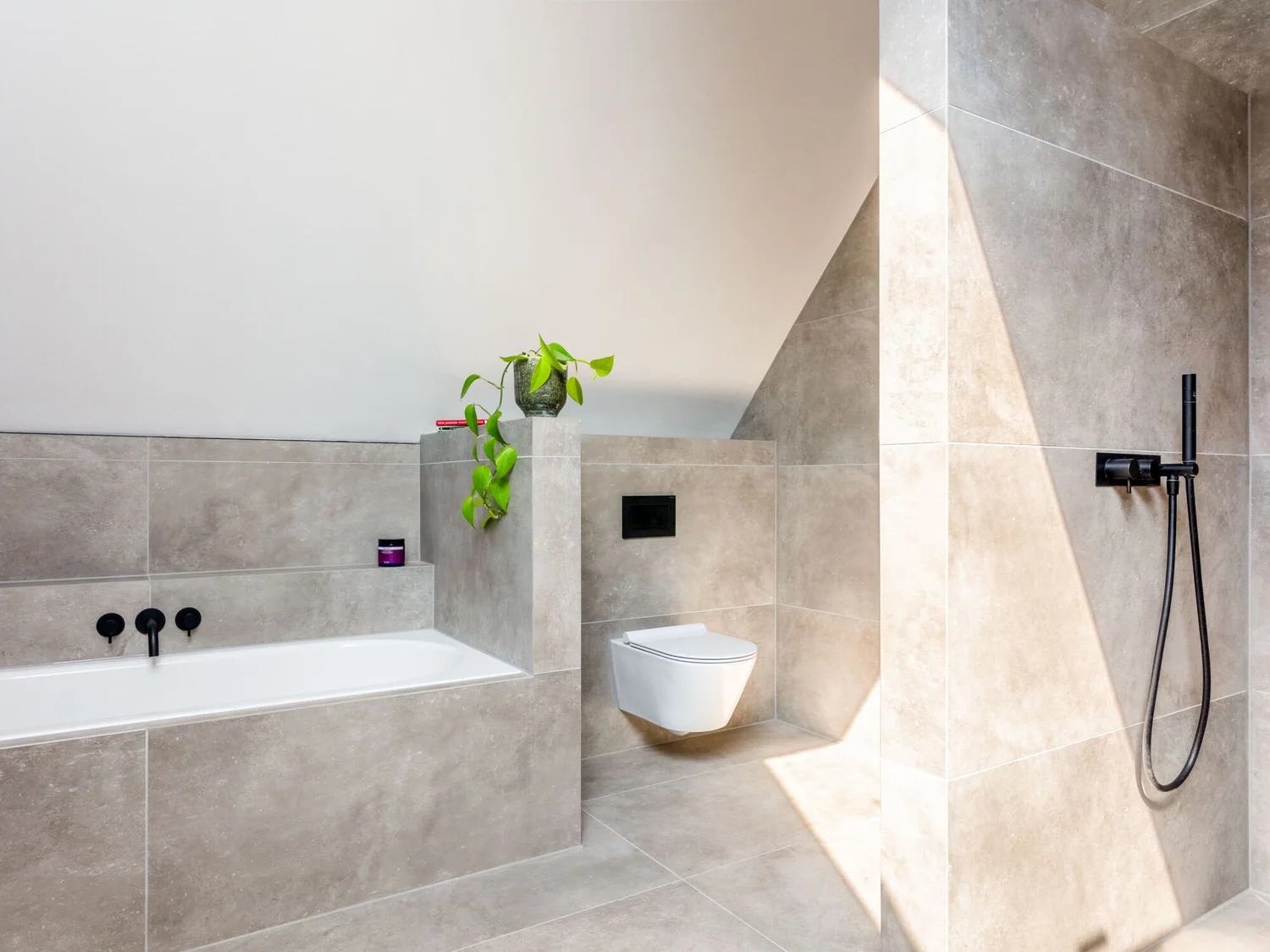 Large-format neutral porcelain tiles fitted across a contemporary bathroom