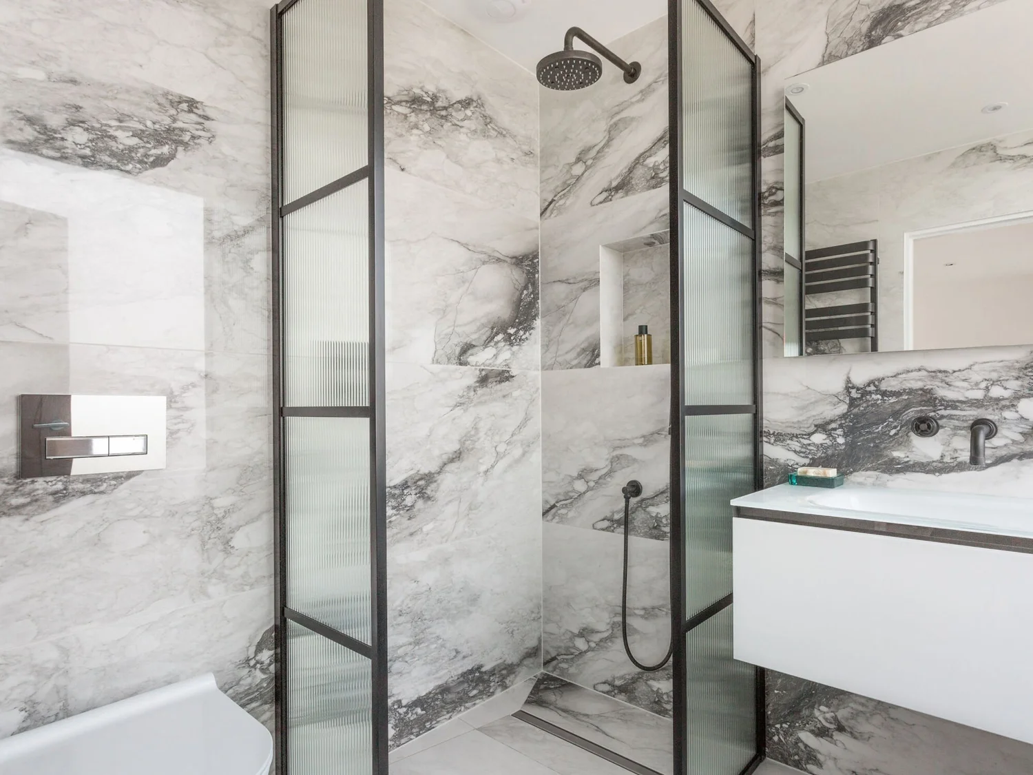 Large-format marble-effect tiles installed around a walk-in shower