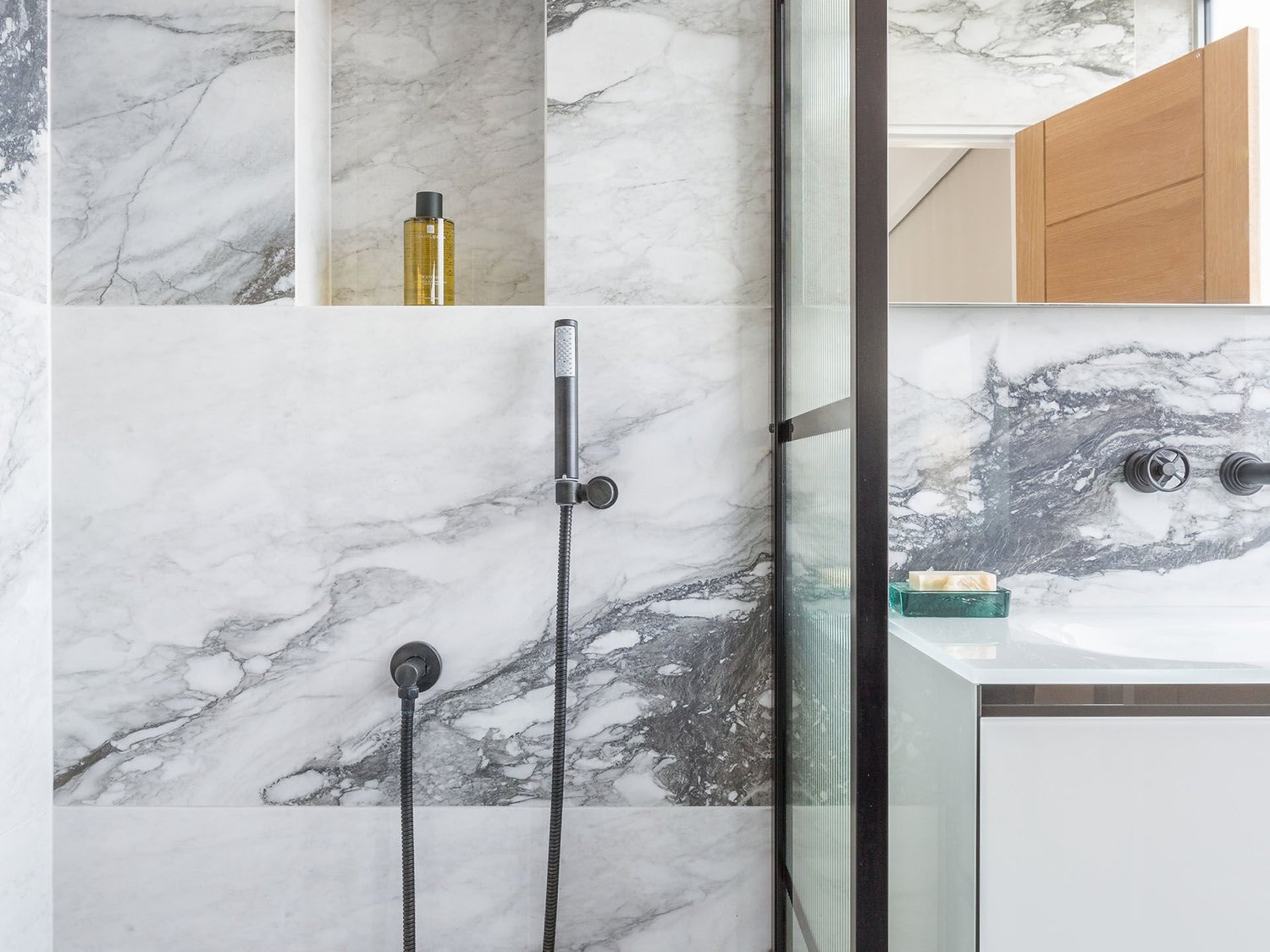 Bookmatched marble-effect large-format slabs installed in a shower enclosure
