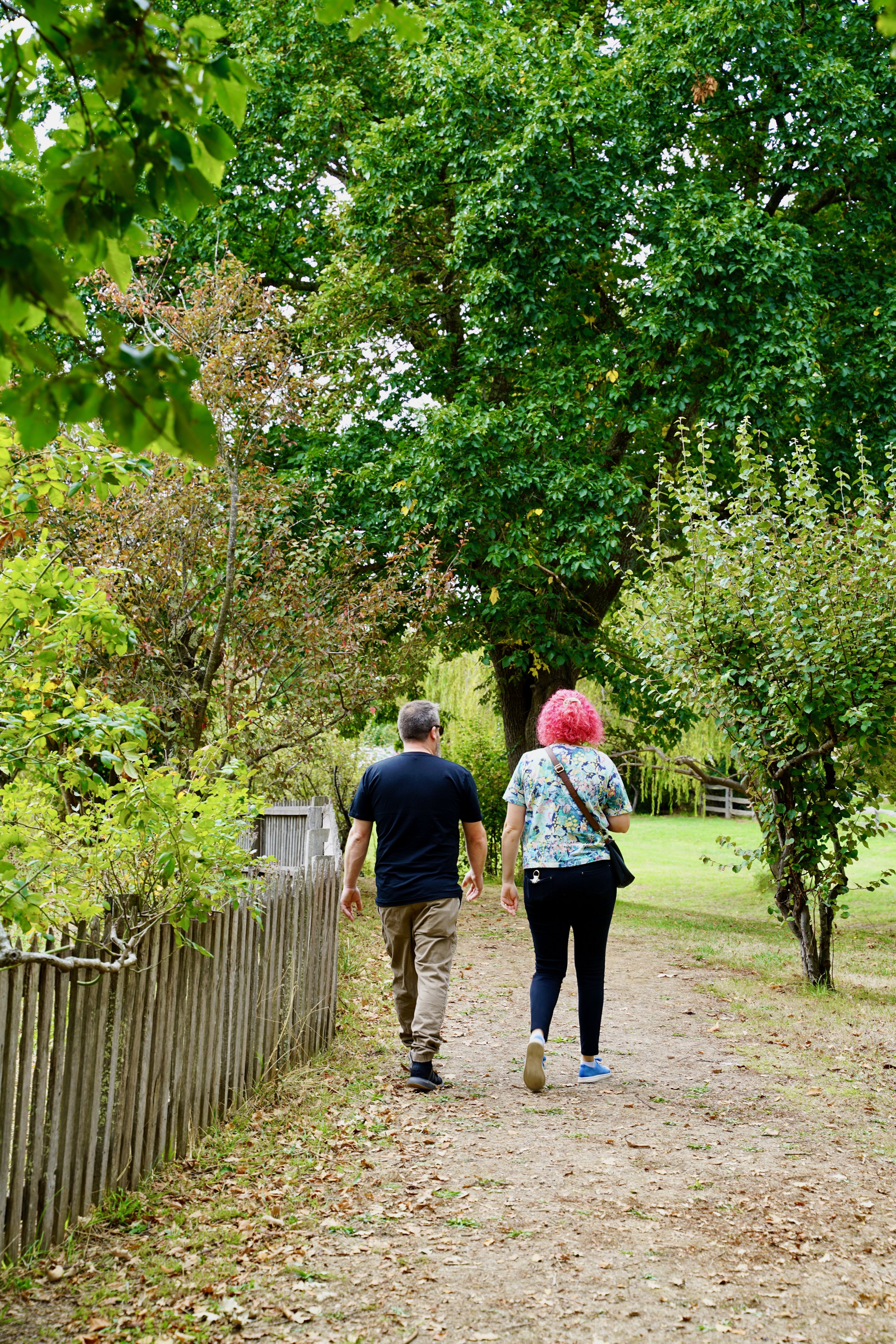 Two women and a man walking down a dirt path through a green park area, surrounded by trees and bushes. Photo: Brook Powell at Gulf Station