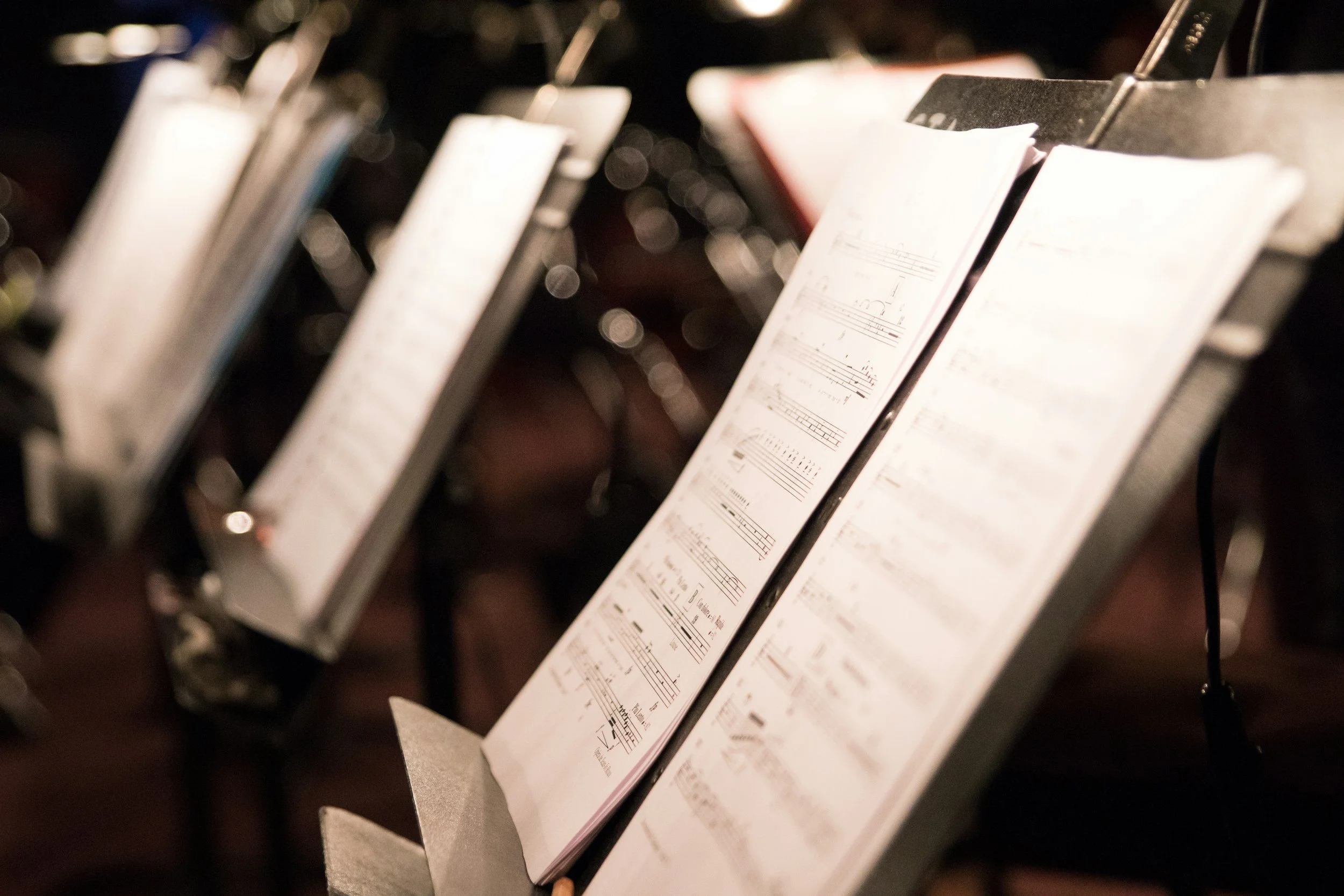 Close-up of sheet music on a music stand, with blurred background.