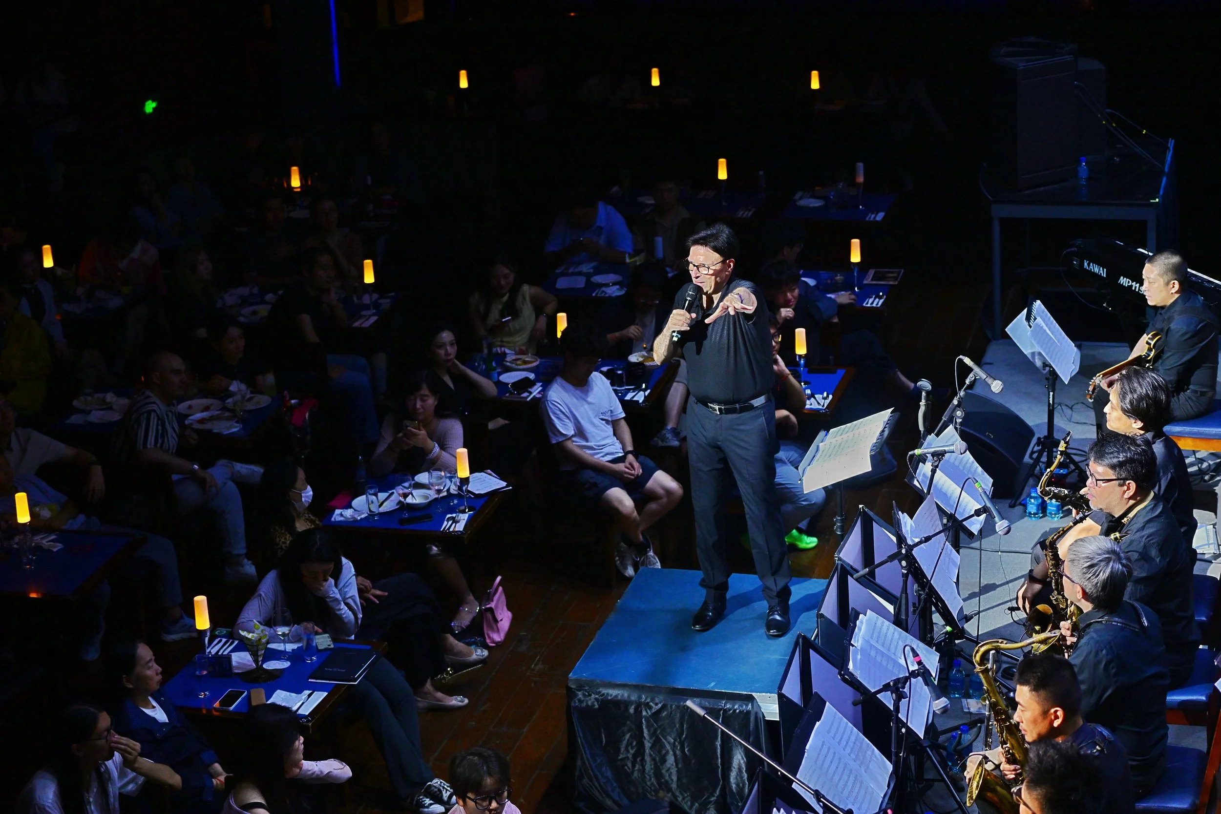 A live music performance with Rolf Becker, conducting and announcing the next music piece.