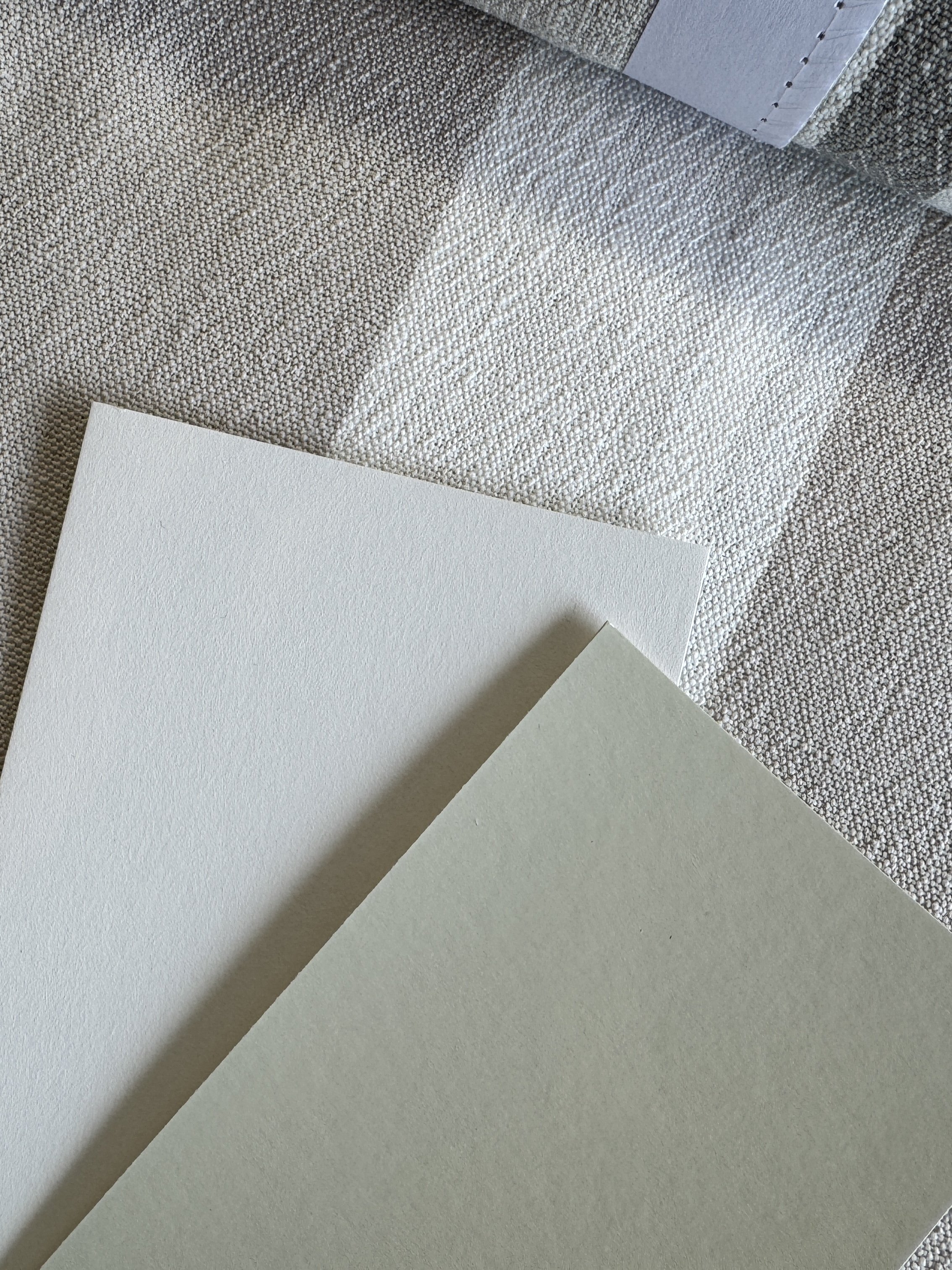 Trois feuilles de papier de texture différente posées sur un tapis gris.