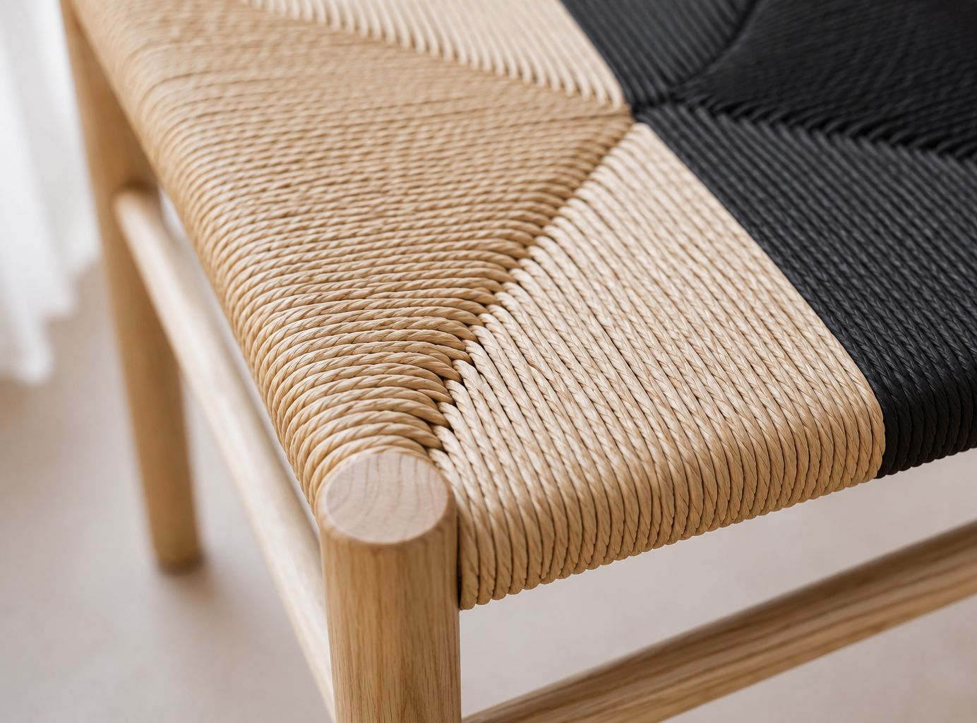 Détail d'un siège en bois avec assise tissée en corde naturelle et noire.