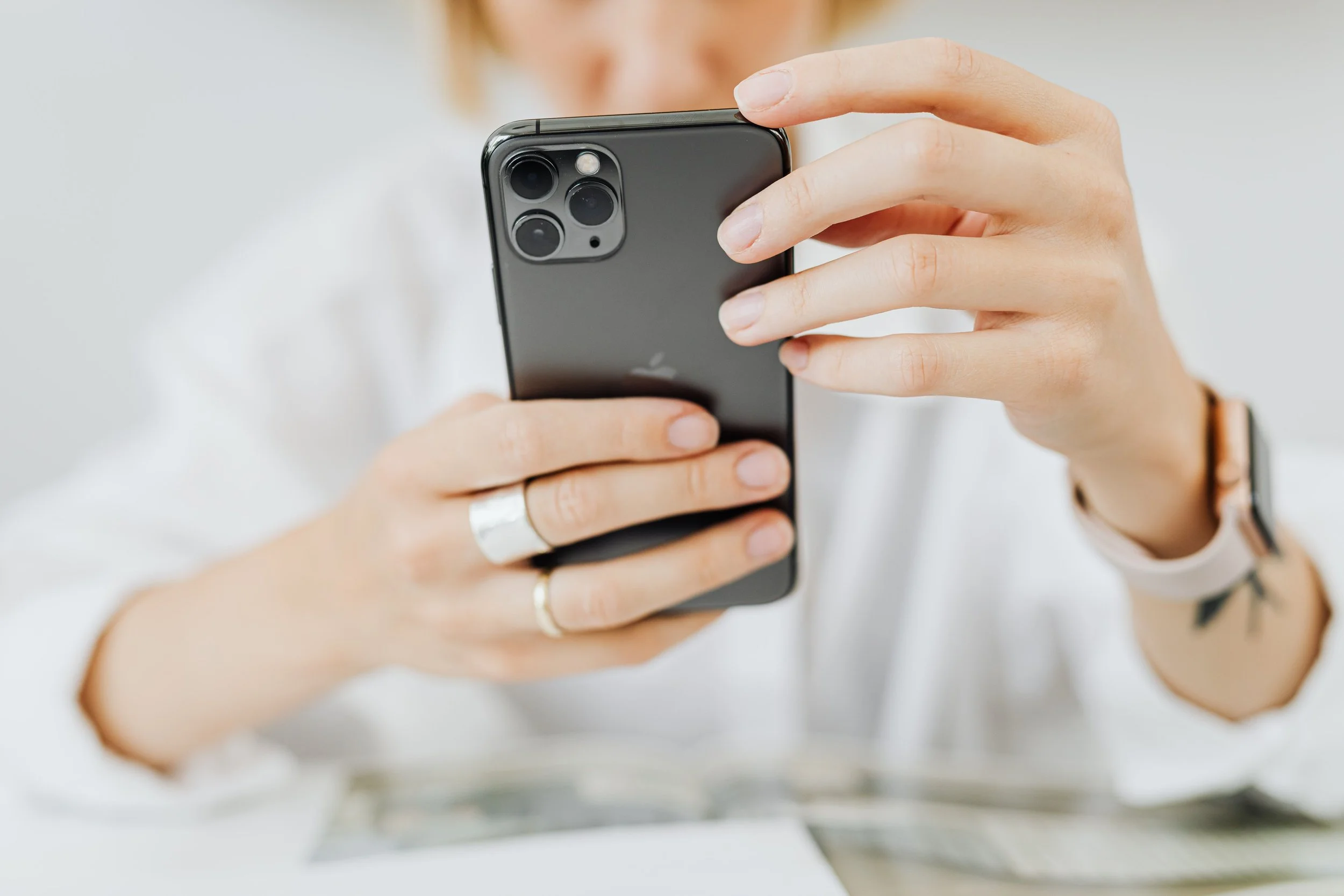 Une personne tenant un smartphone noir avec un triple appareil photo à l'arrière, en train de le regarder ou de l'utiliser.