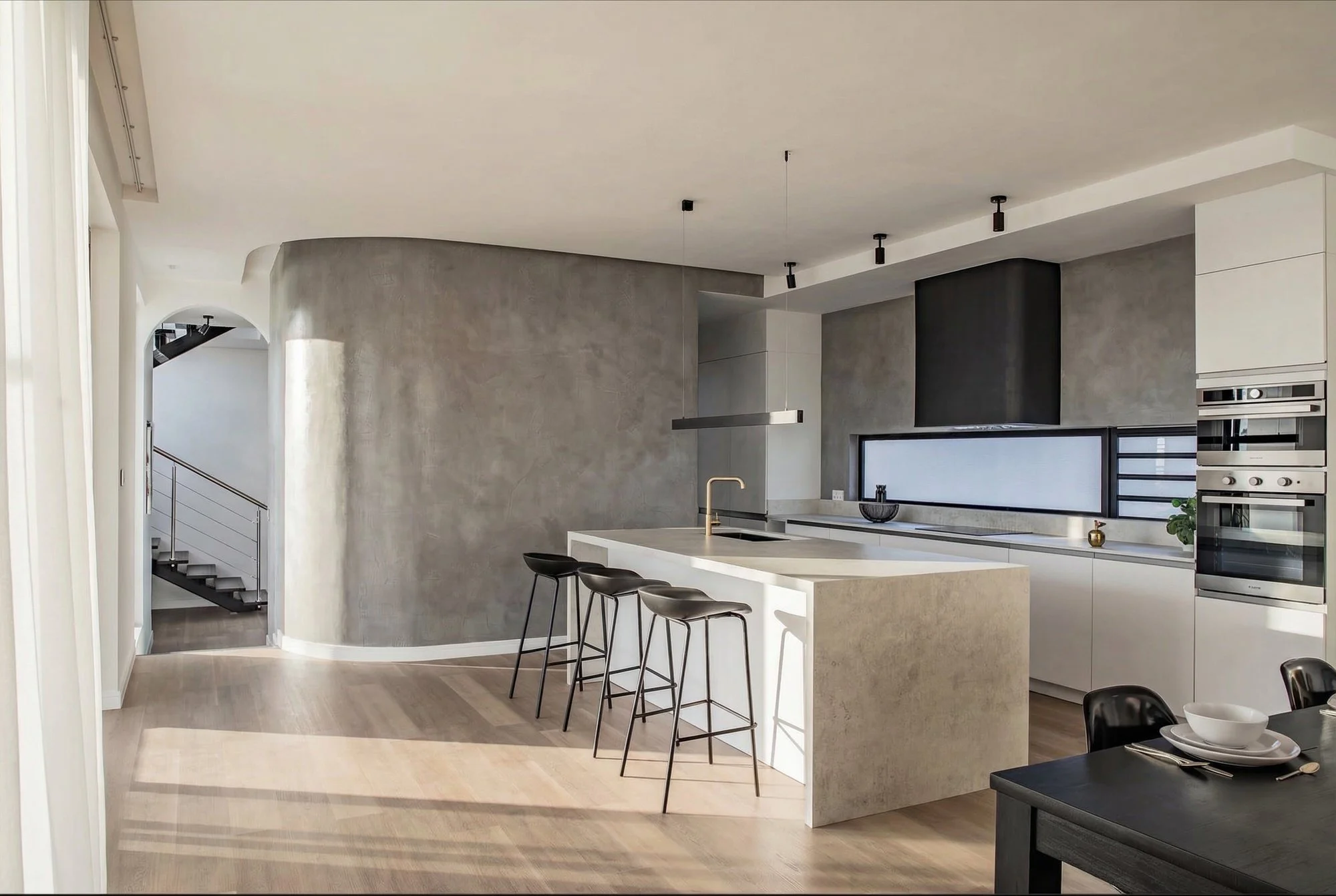 Iluka II — minimalist kitchen with curved walls and concrete textures.