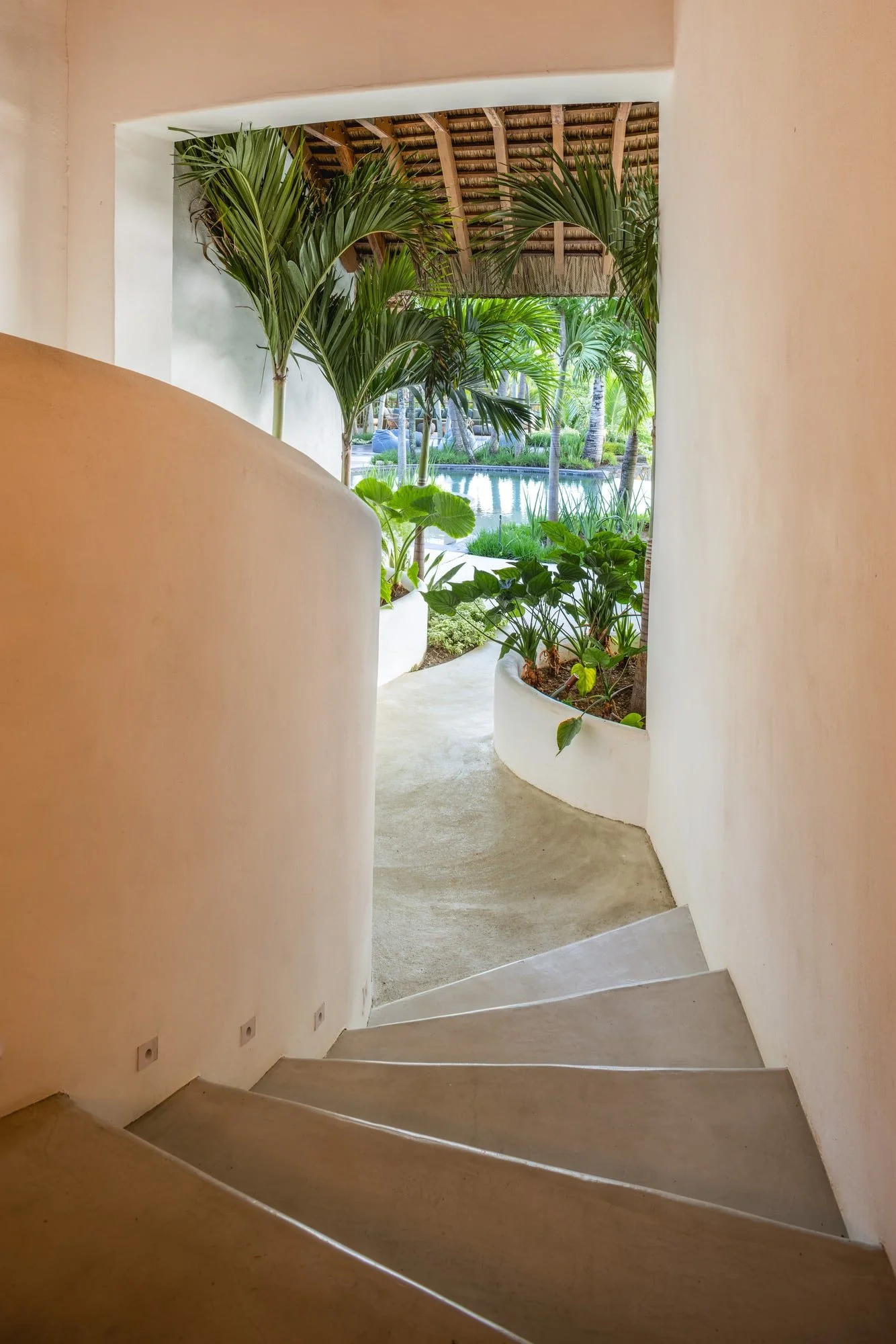 Muse Villa — curved white stairway framed by tropical planting.
