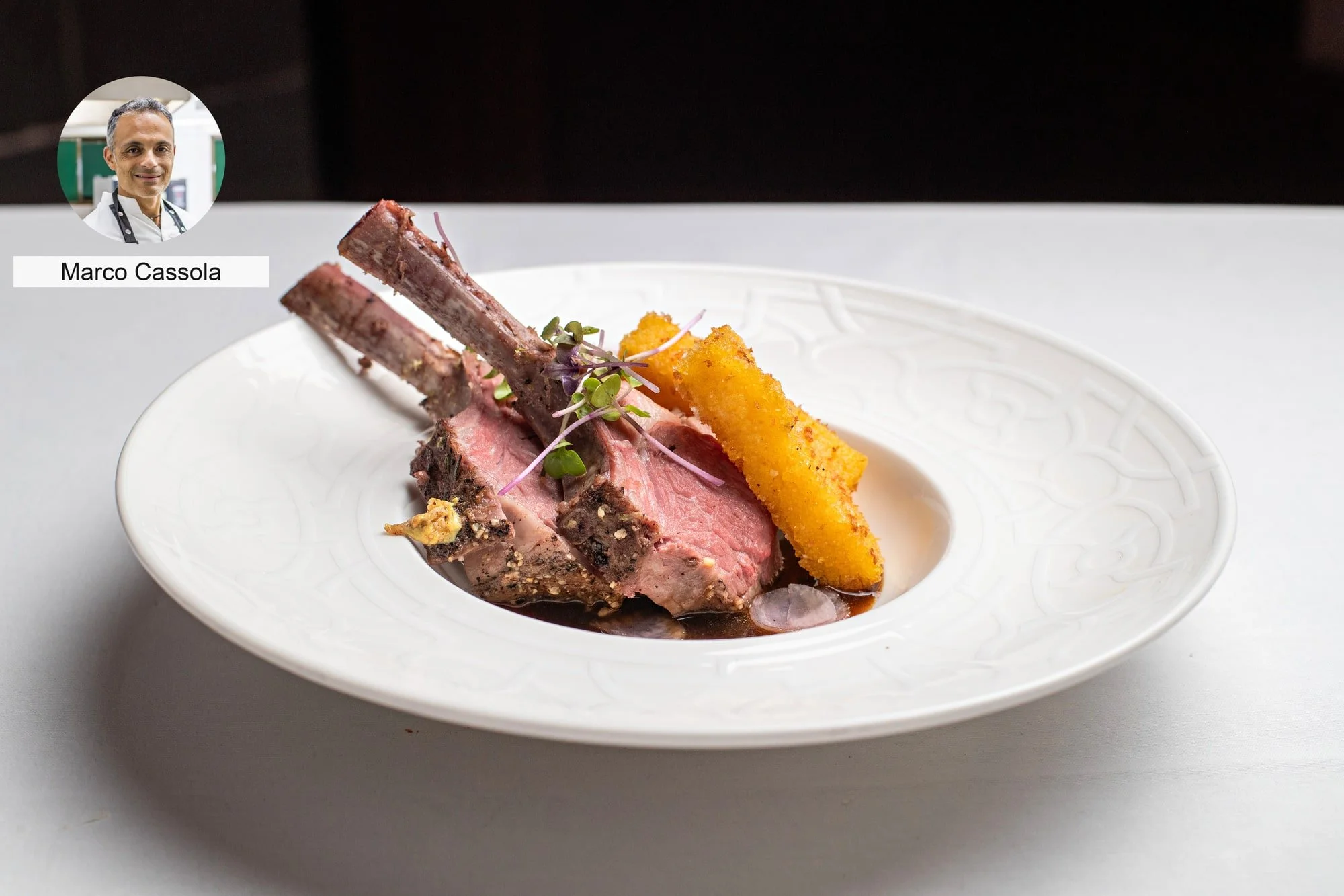 Roasted rack with golden garnish by chef Marco Cassola, presented for fine dining.