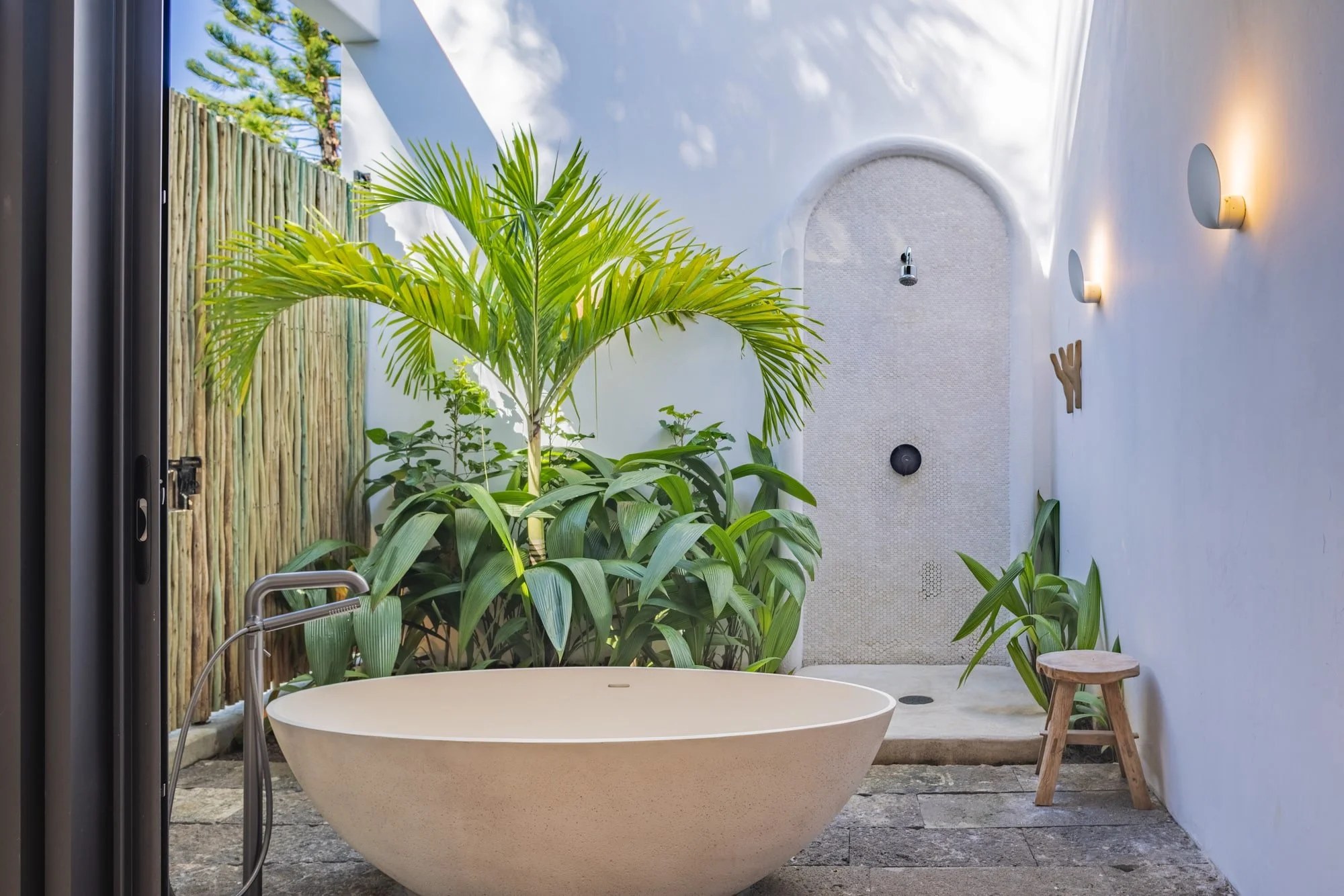 Muse Villa — outdoor bathroom enclosed by white walls and tropical planting.