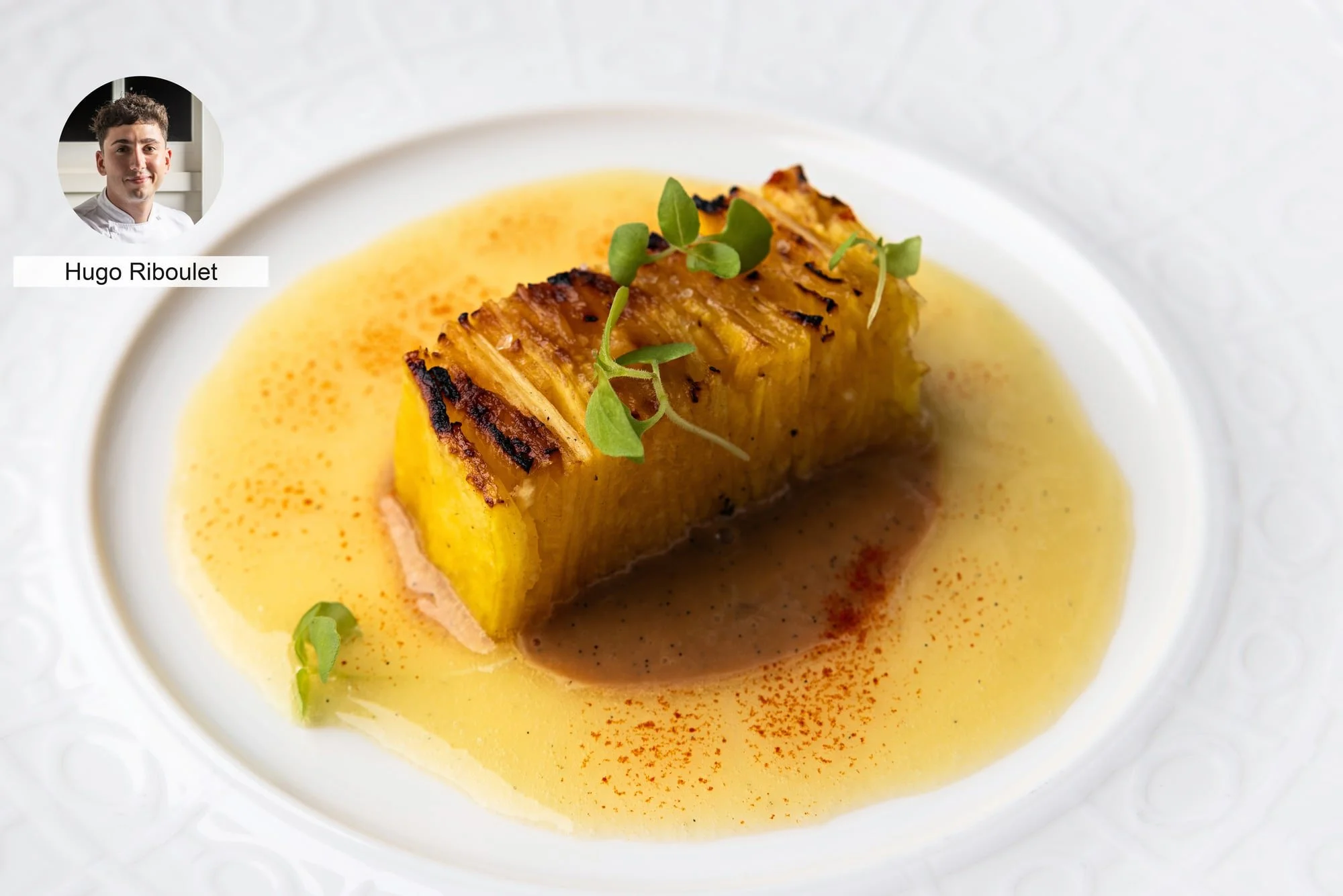 Golden layered dish with sauce by chef Hugo Riboulet, photographed for a culinary event.