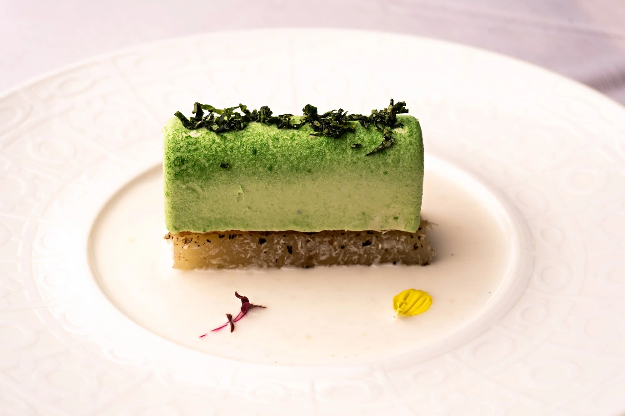 Green layered culinary creation presented on a minimalist plate.