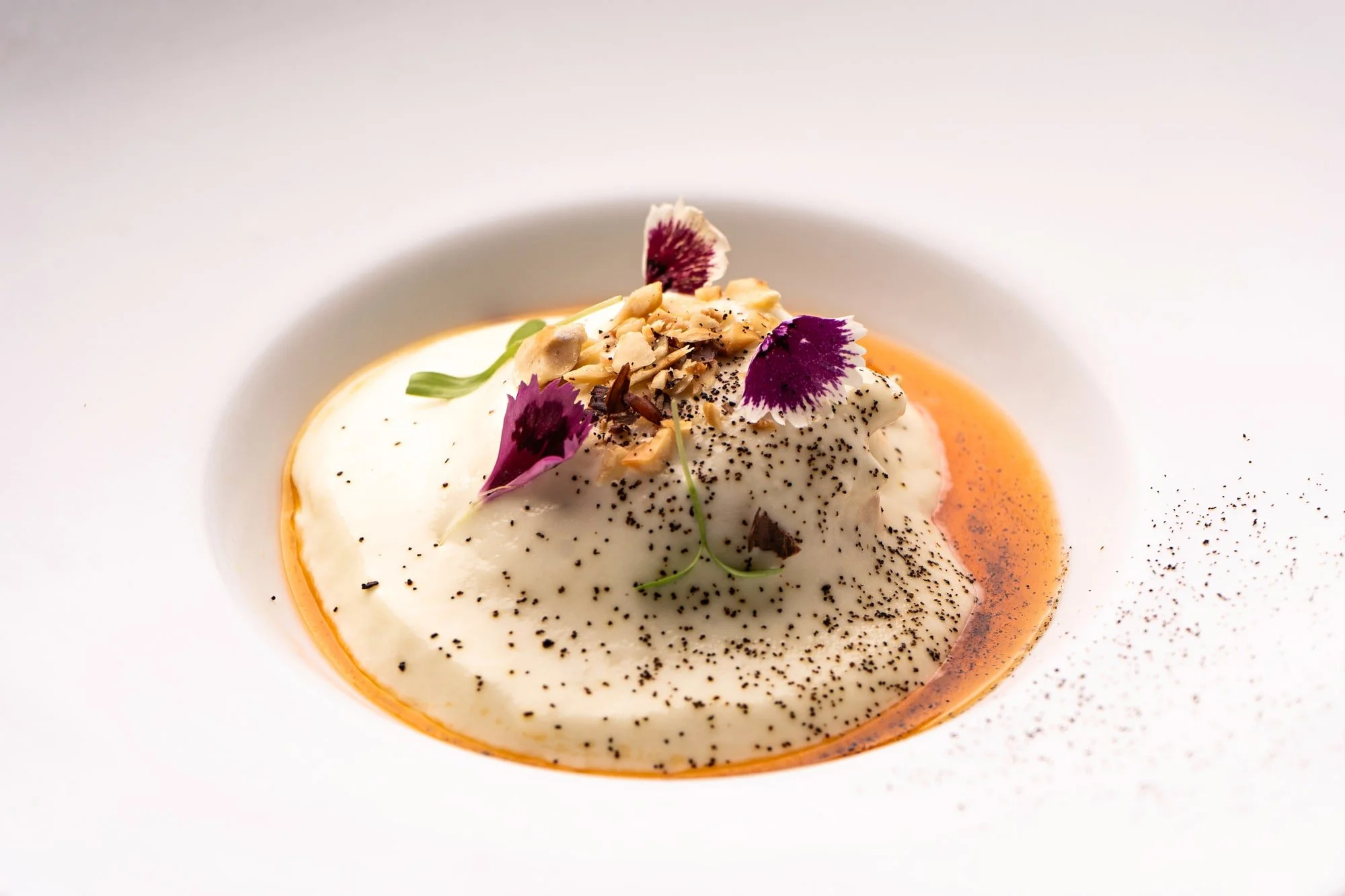 Foamy starter with edible flowers, photographed as a fine-dining creation.
