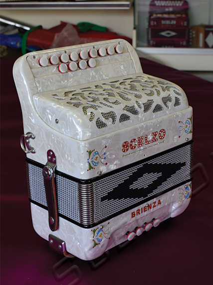 Una scatola decorativa a forma di cilindro con dettagli colorati e scritte come 'SCELZO' e 'BRIENZA', con elementi di design che ricordano una radio vintage, posizionata su una superficie rossa con sfondo di armadietti e oggetti.