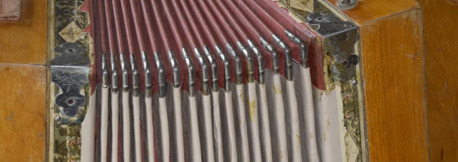 Un vecchio pianoforte in legno con le corde visibili e il telaio interno.