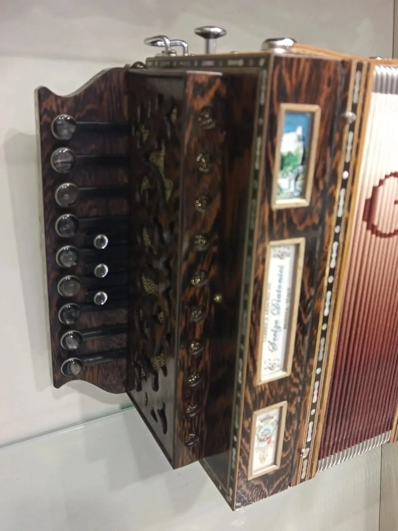 Una scatola di legno decorata con disegni e immagini di case, con manopole e ripiani interni, probabilmente un giocattolo o un oggetto decorativo.