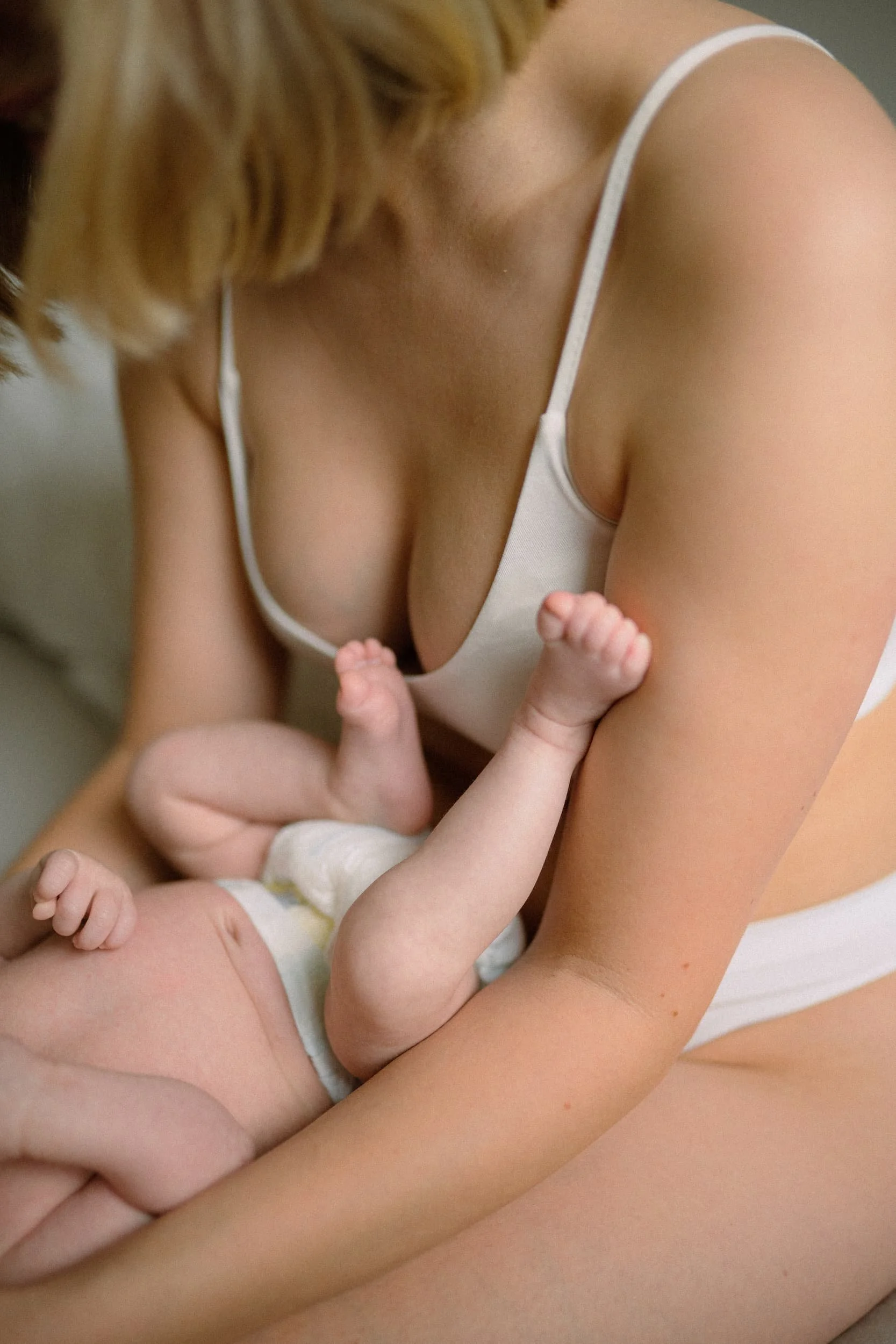 Nahaufnahme von einer Mutter, die ihr Baby hält, mit Fokus auf die Arme und Hände.