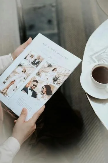 Person holding a magazine with fashion photos while sitting at a table with a cup of coffee.