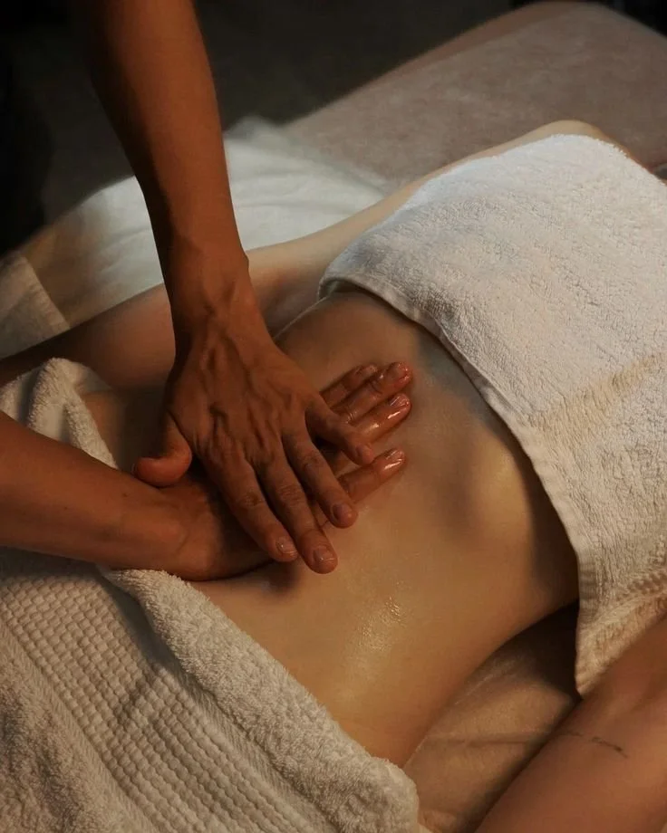 Une personne reçoit un massage sur le dos, recouverte d'une serviette blanche, dans un environnement de spa ou de massage.