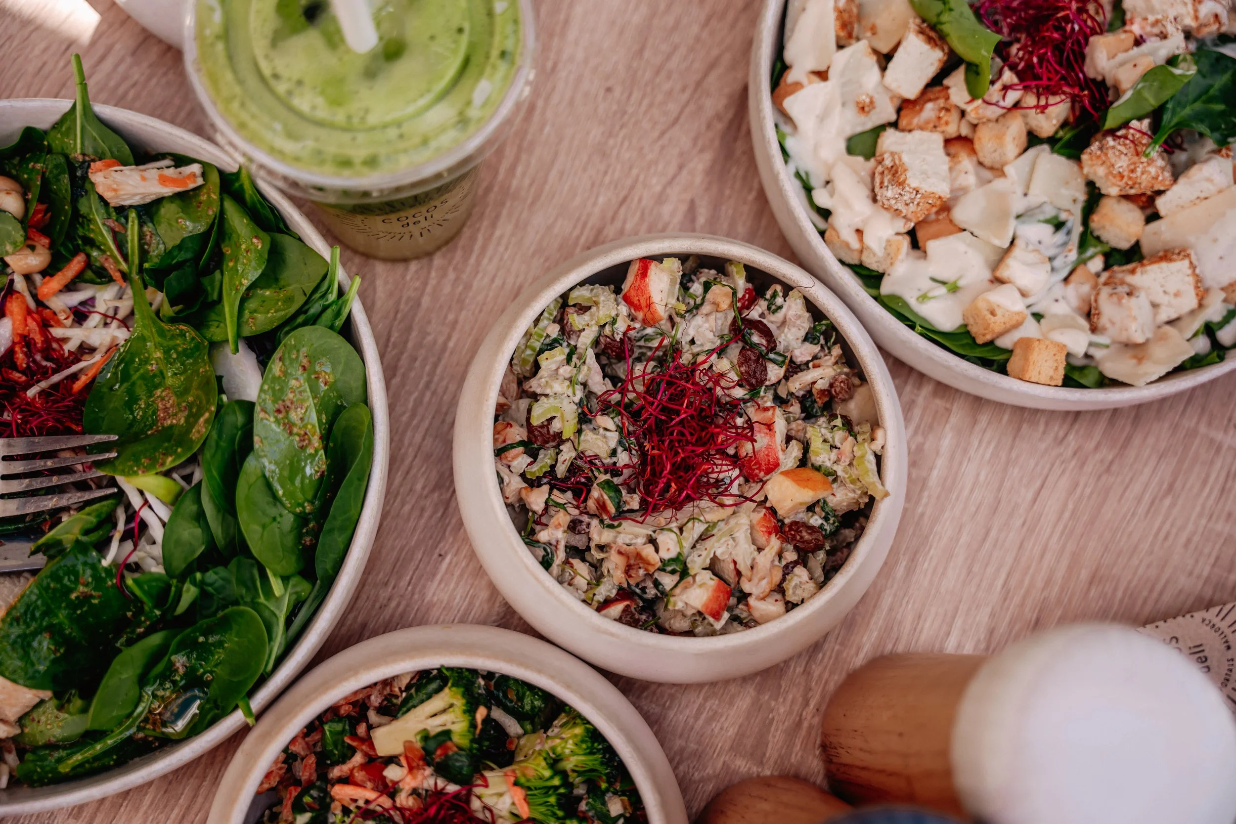 Assorted salads and green drink on wooden table