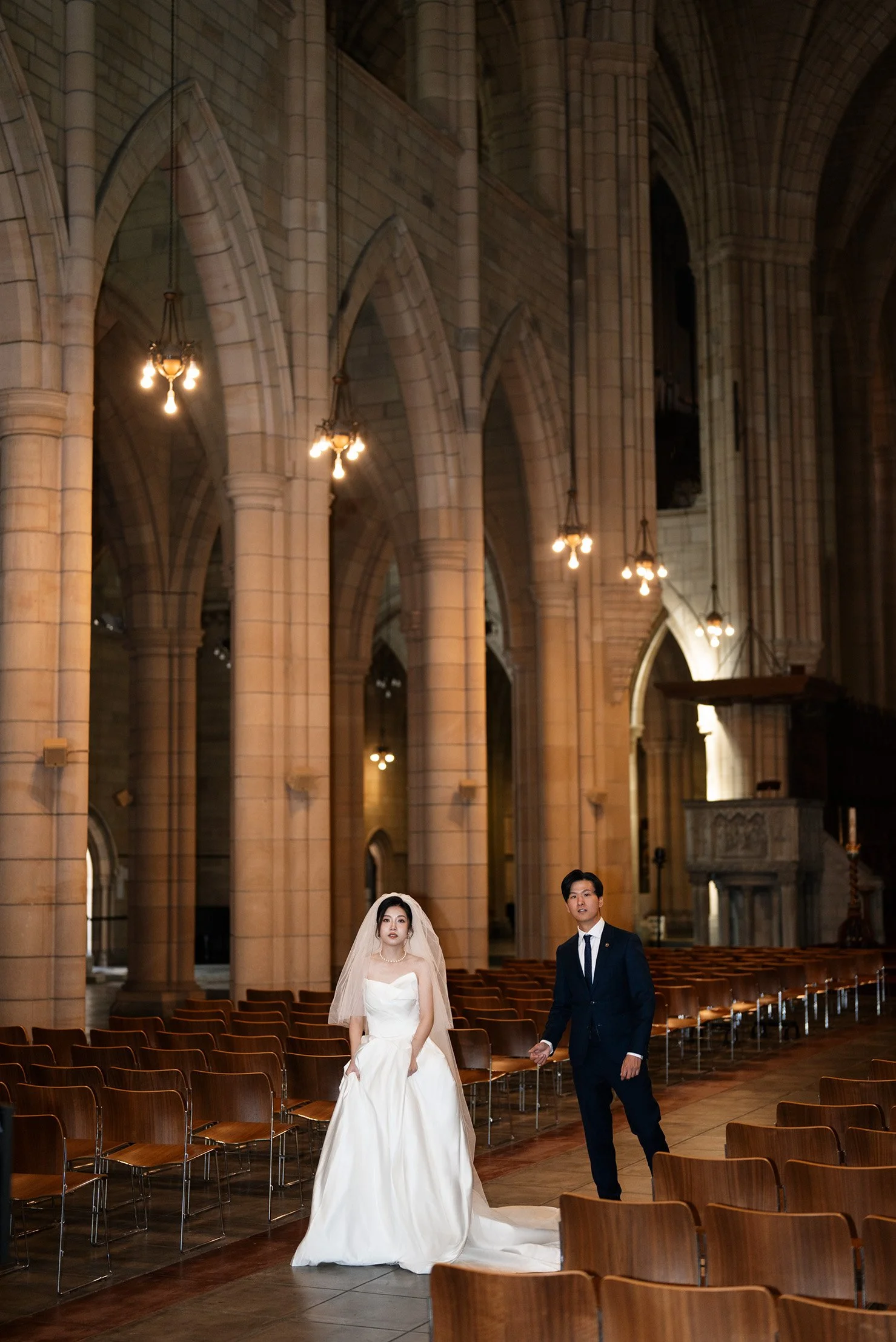 bride Cassie holding her dress and groom both look at the camera