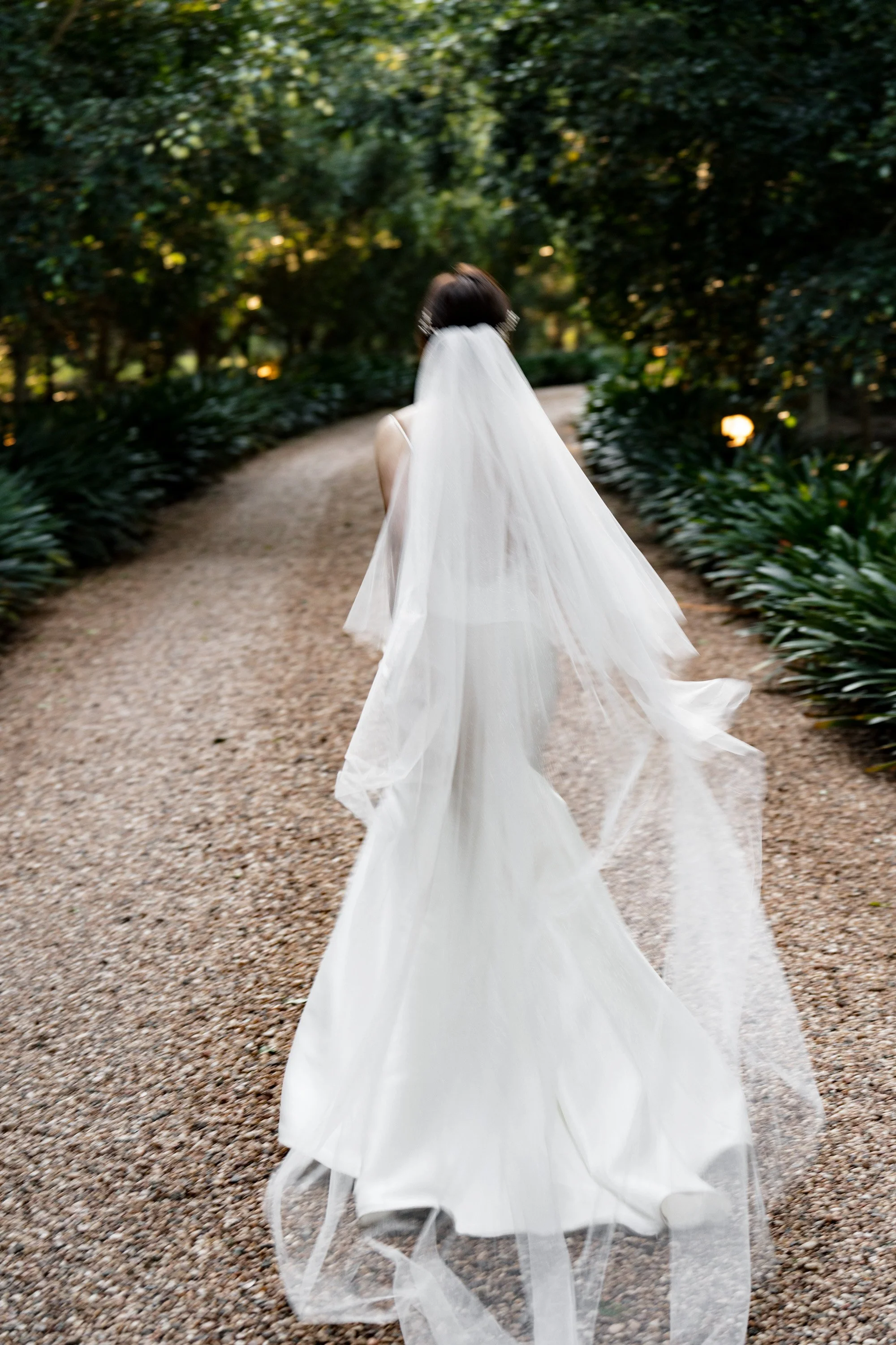Bride Vicky running playfully away from the camera at Gabbinbar Homestead, her wedding dress flowing gracefully behind her. Captured by Brisbane wedding photographer Whistler, the moment highlights a sense of joy, freedom, and the romantic charm of t