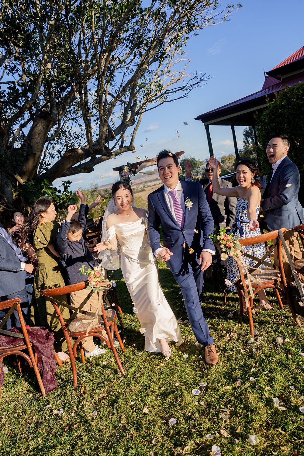 Eric holding Flora's hand walking down and all the guests cheers for them