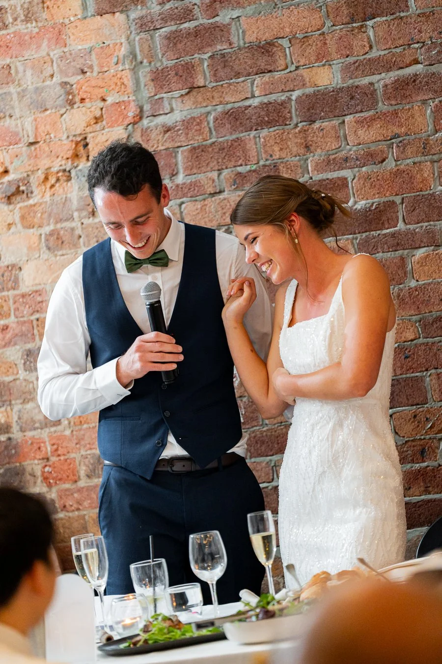 Giordan holding a mic in his speach in reception and bride Sonya stand next to him