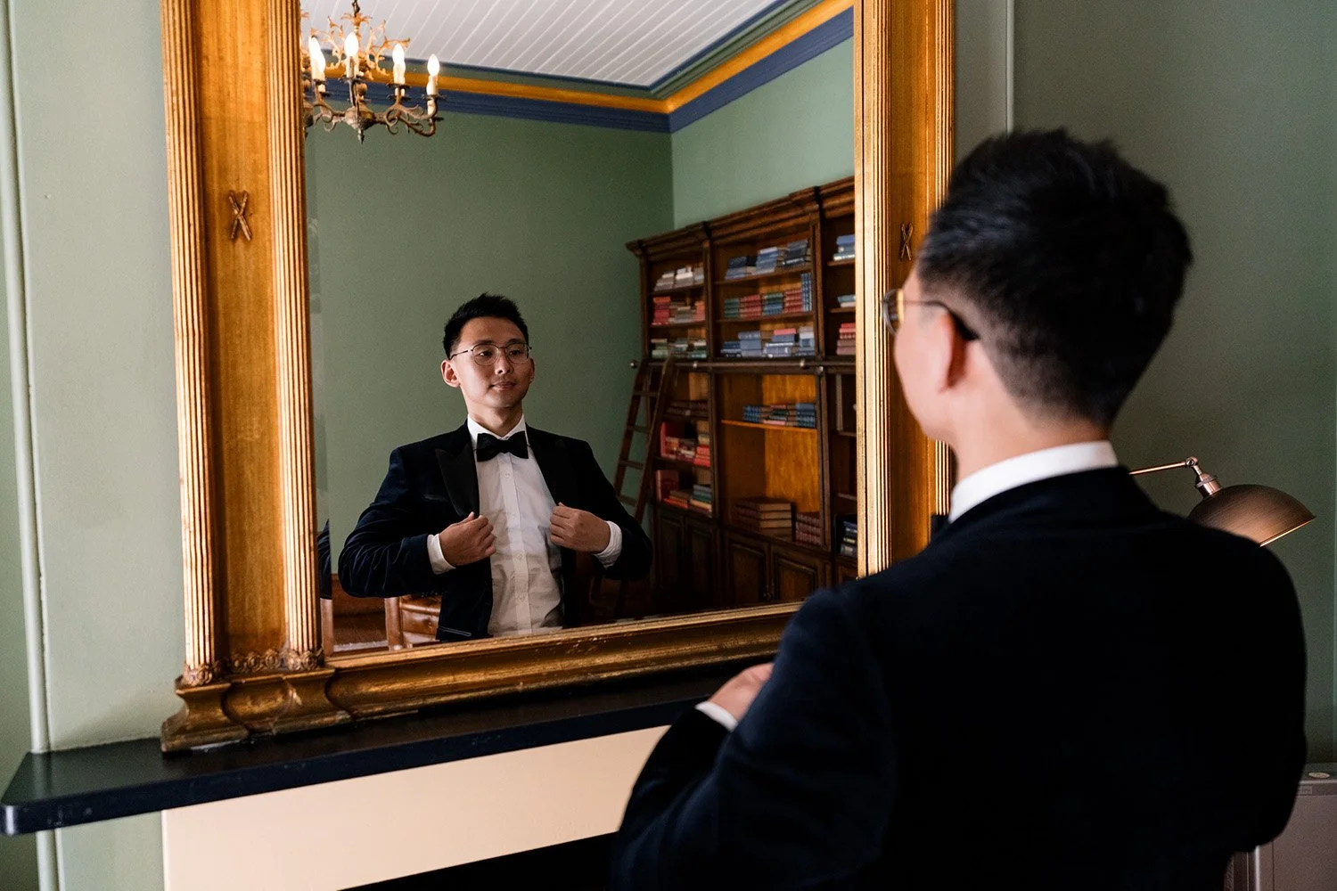groom Brus look at himself through mirror and adjusting his jacket