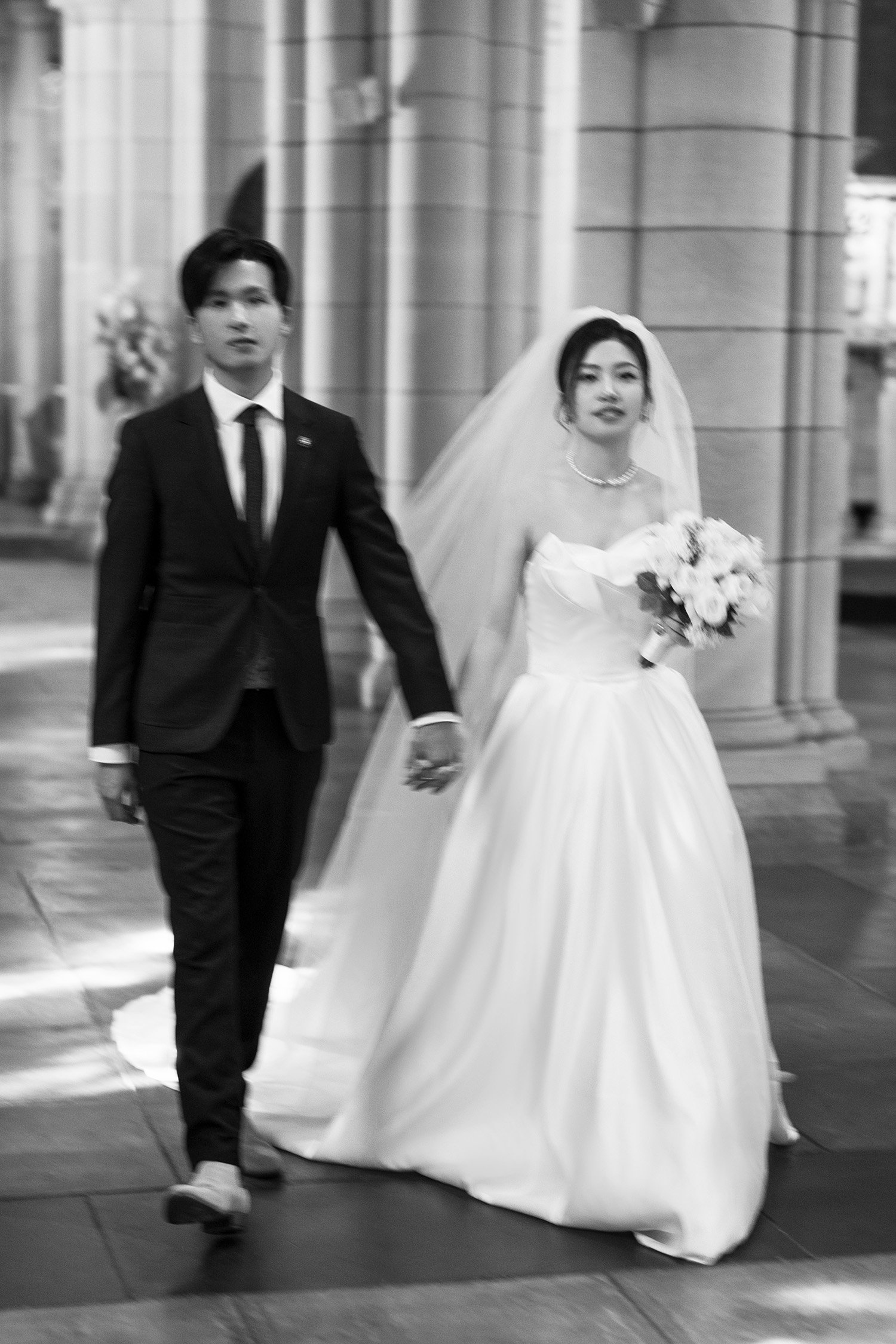 bride and groom walking together and they both look at the camera in St John's Cathedral in Brisbane