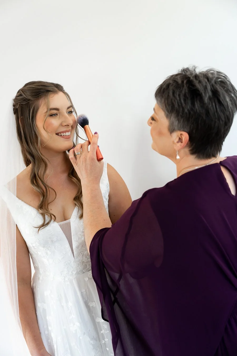 bride Chiarra's mum using the brush her face while they look at each other