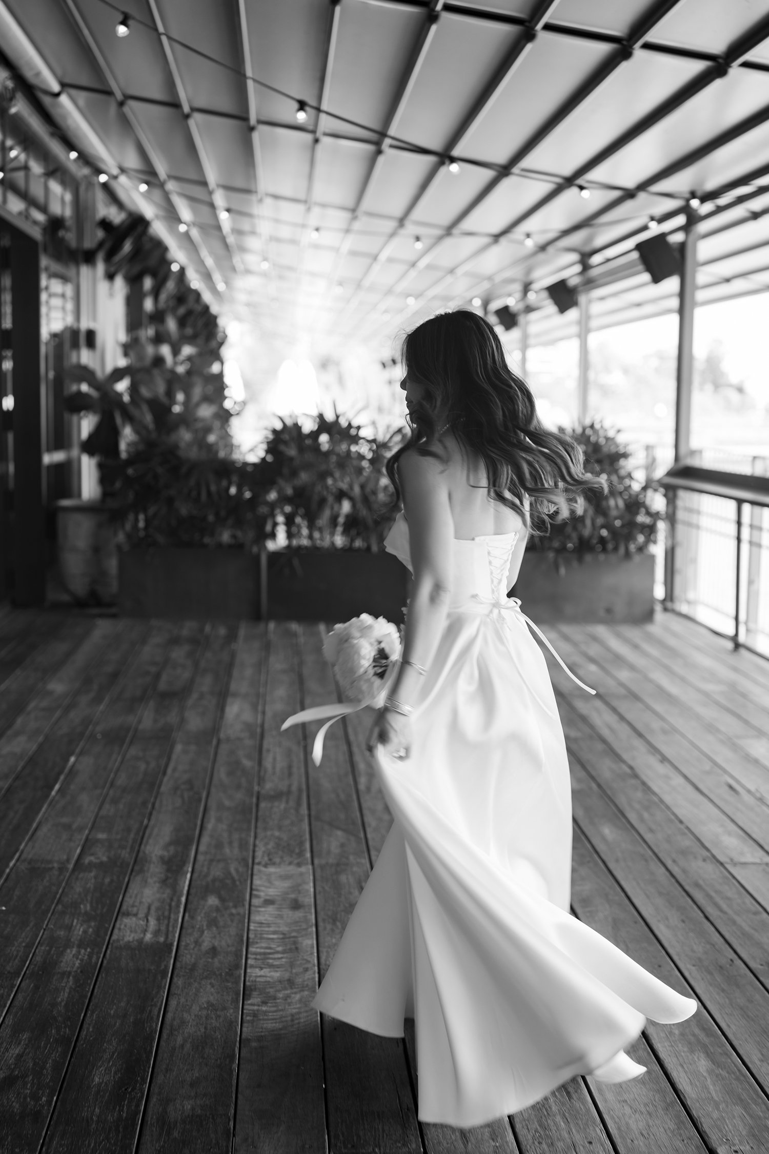 Bride Tiffy running away from the camera, gracefully holding up a part of her wedding dress as it flows behind her. The movement adds a sense of freedom and excitement, capturing the joy and energy of the moment while highlighting the elegance of her