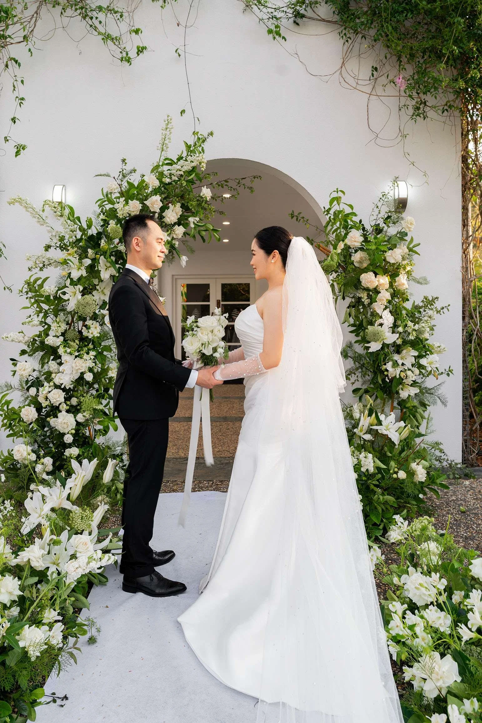Wendy and Alex look at each other and holding hands facing to each other, flower in middle