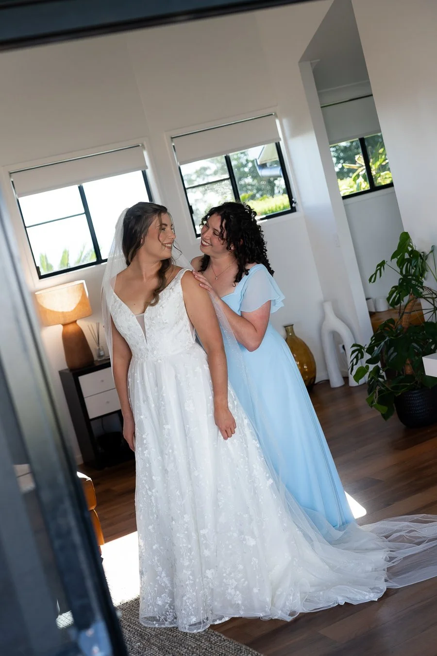 Bride's sister holding Chiarra's shoulder from back and they both look at each other