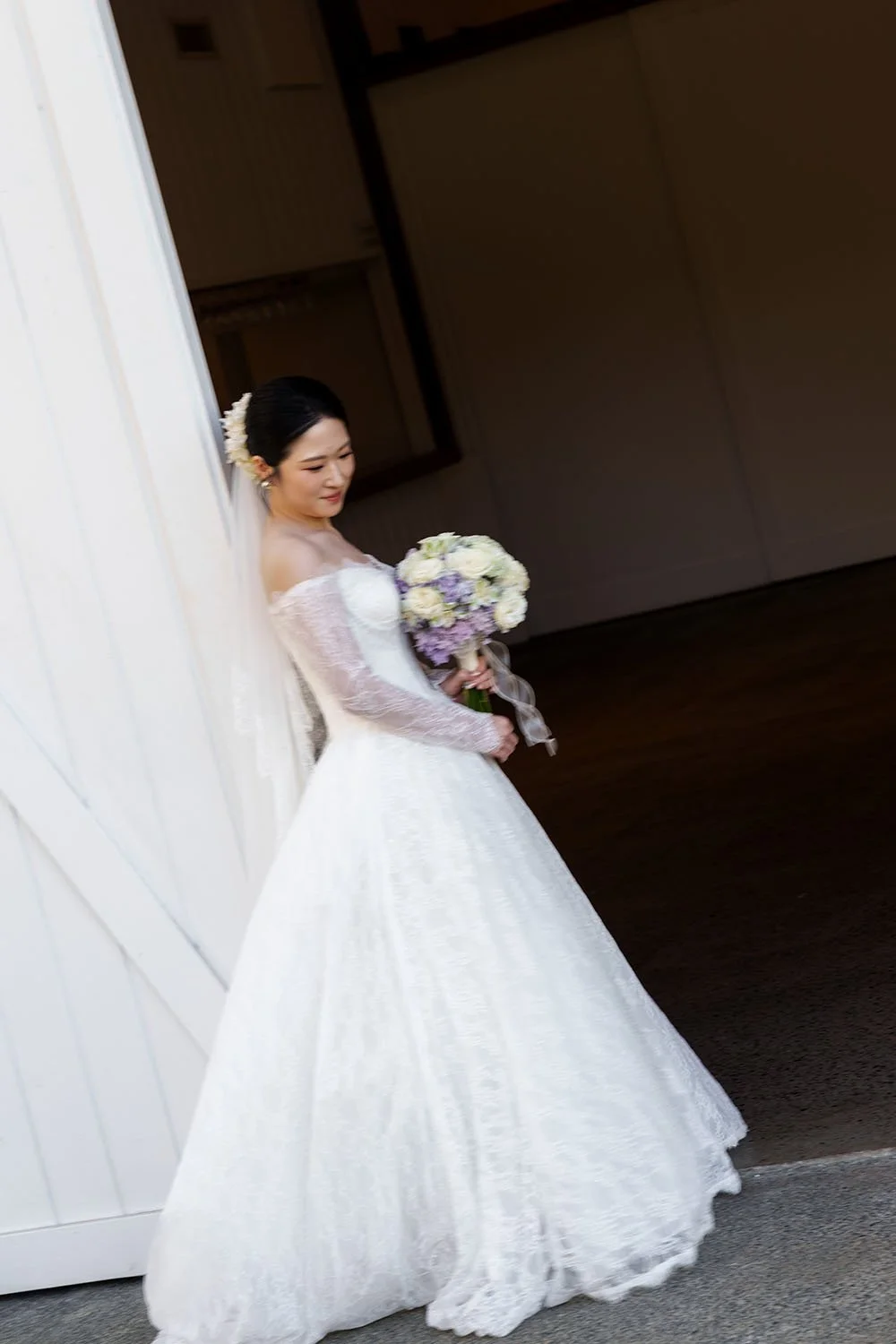 Lisa holding her flower leaning on a white barn door