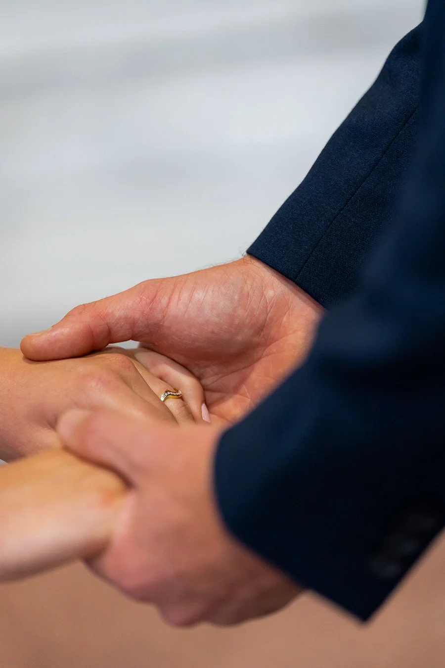 The groom holds the bride’s hand, revealing her wedding ring