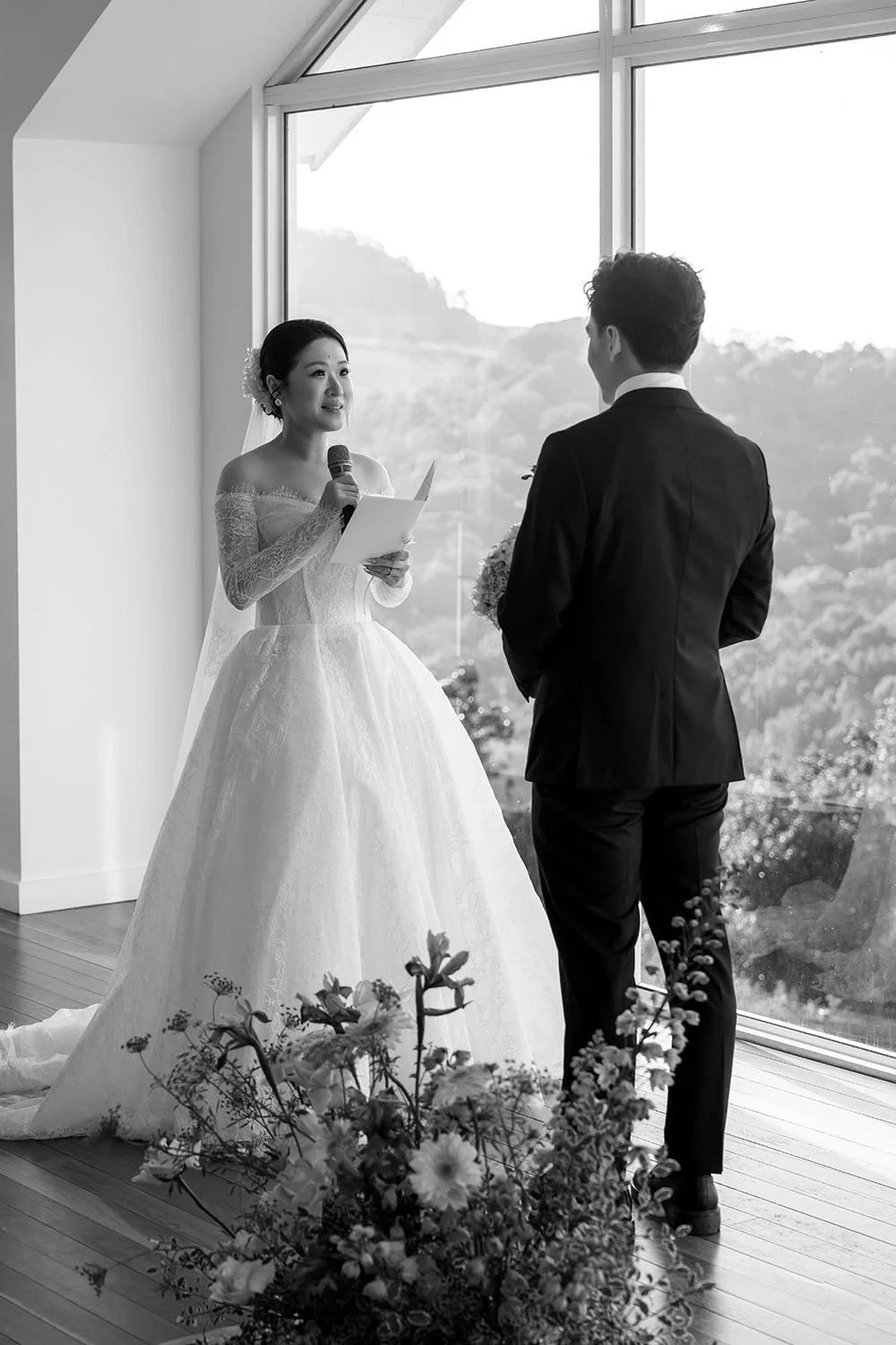 Lisa holding a mic reading her vows while look at Michael