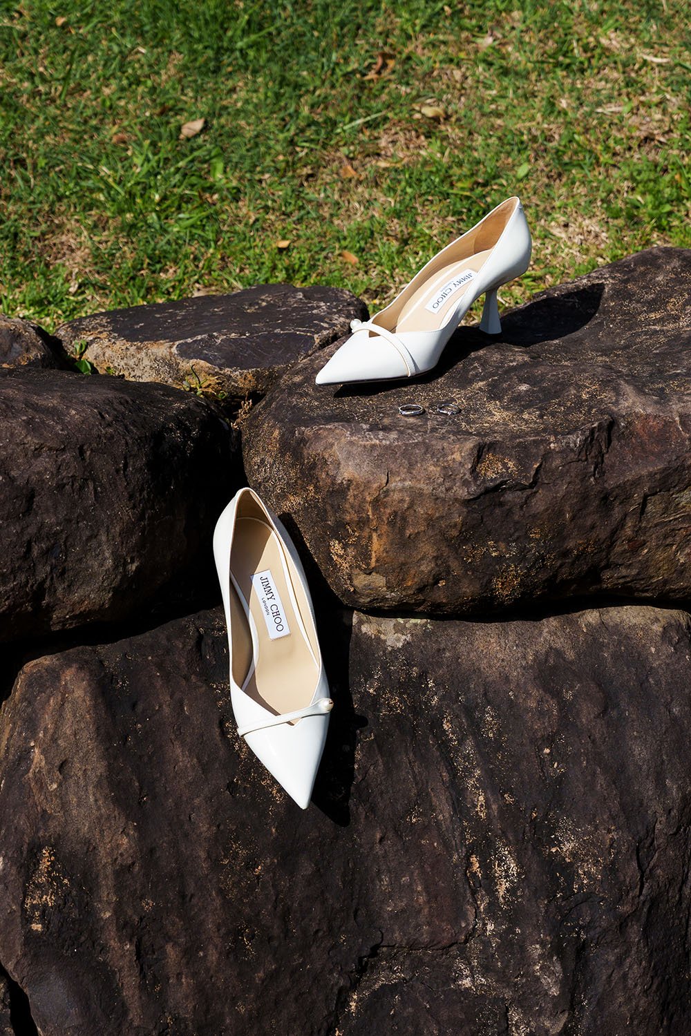 Lisa's wedding shoes on rocks with their wedding wring next to them