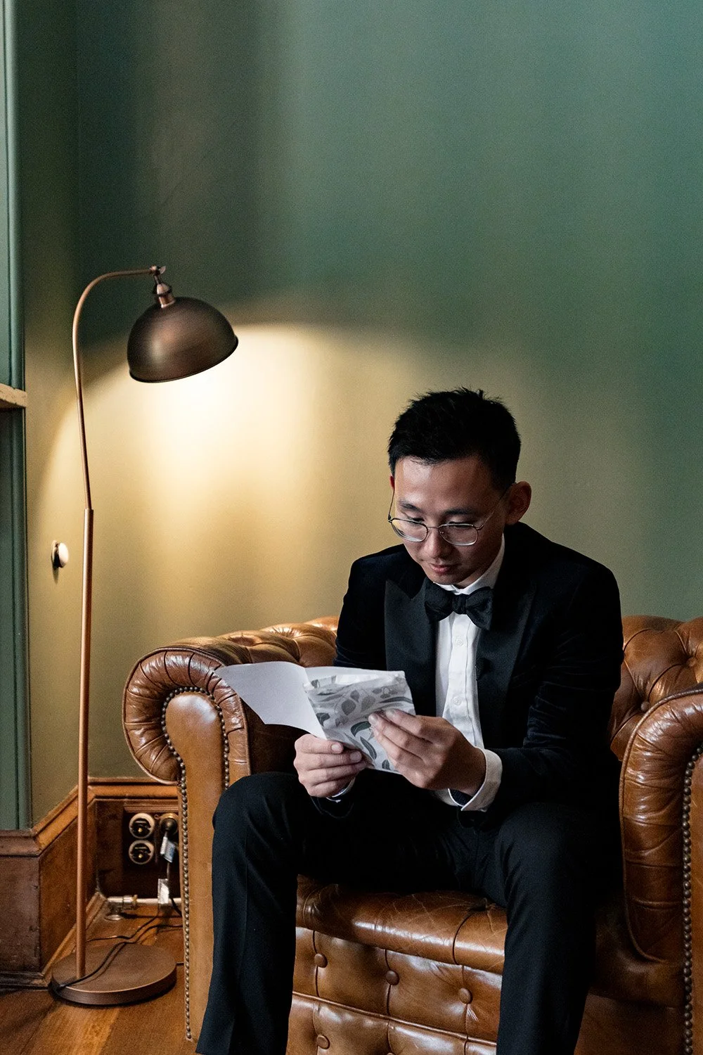 groom Brus sitting on the a sofa and reading the love letter from bride
