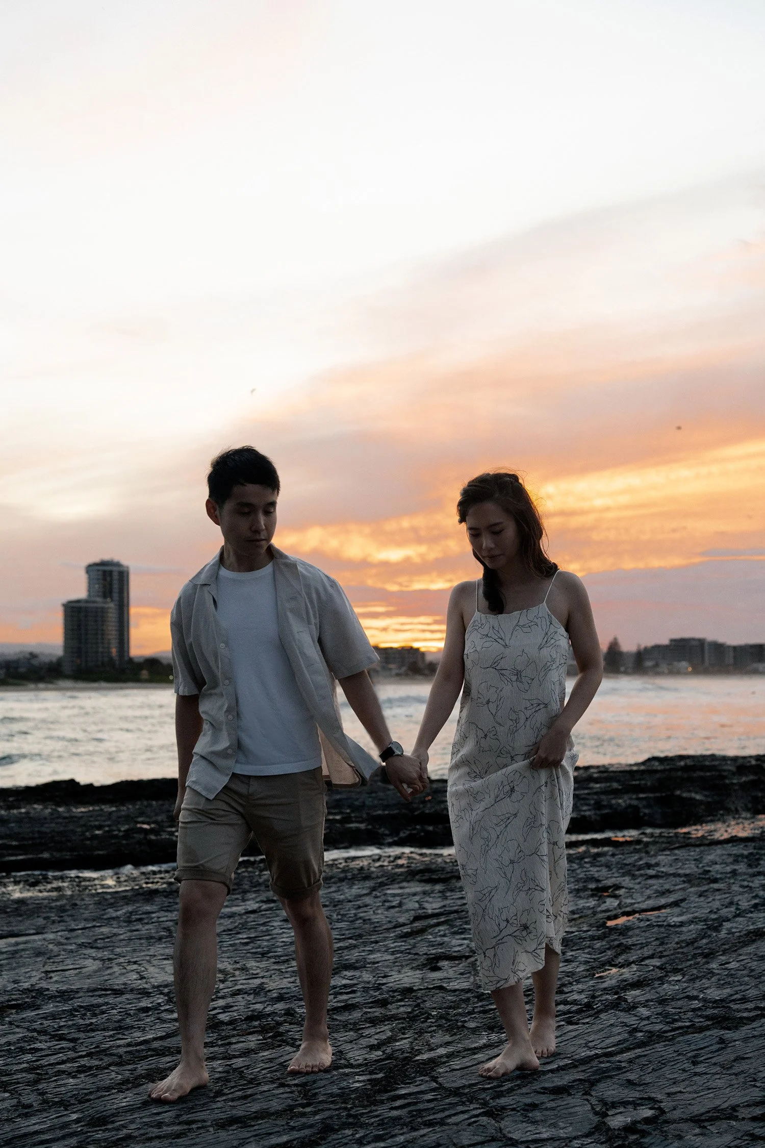 Paul holding Krystel's hand walking on rocky surface in Gold Coast in a Brisbane engagement photography session