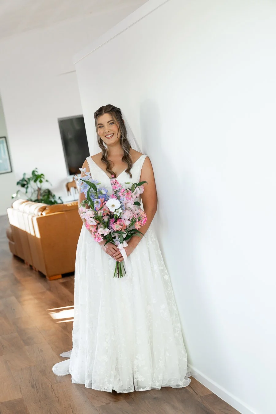 bride Chiarra leaning on the wall with two hands holding the flower look at the Brisbane wedding photographer Whistler li