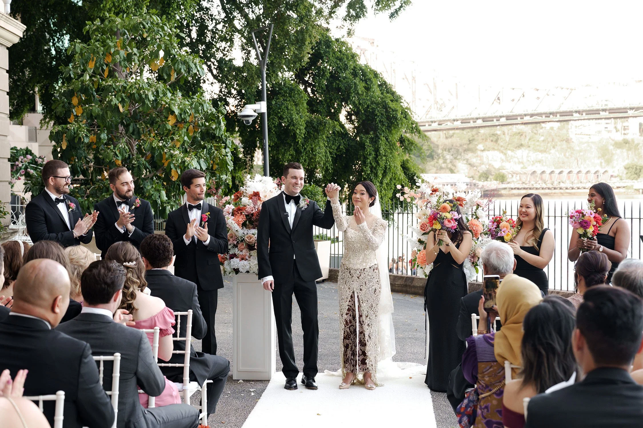 bride Nori raising up her hand to her guests, and everyone claps for them
