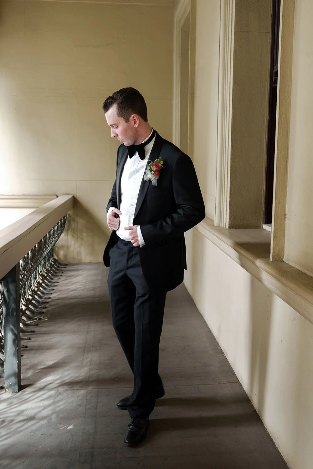 groom Cliffe two hands holding his jacket with one step forward while look down