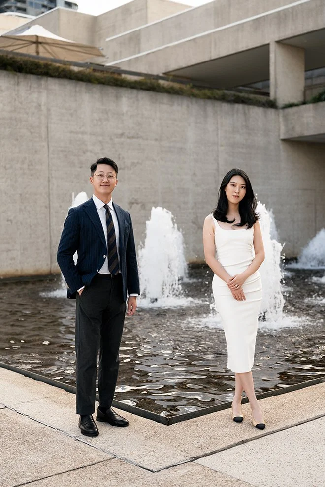 Dave and Kath stand next to each other look at the Brisbane wedding photographer Whistler Li, Dave hands inside pants pocket and Kath hands at front